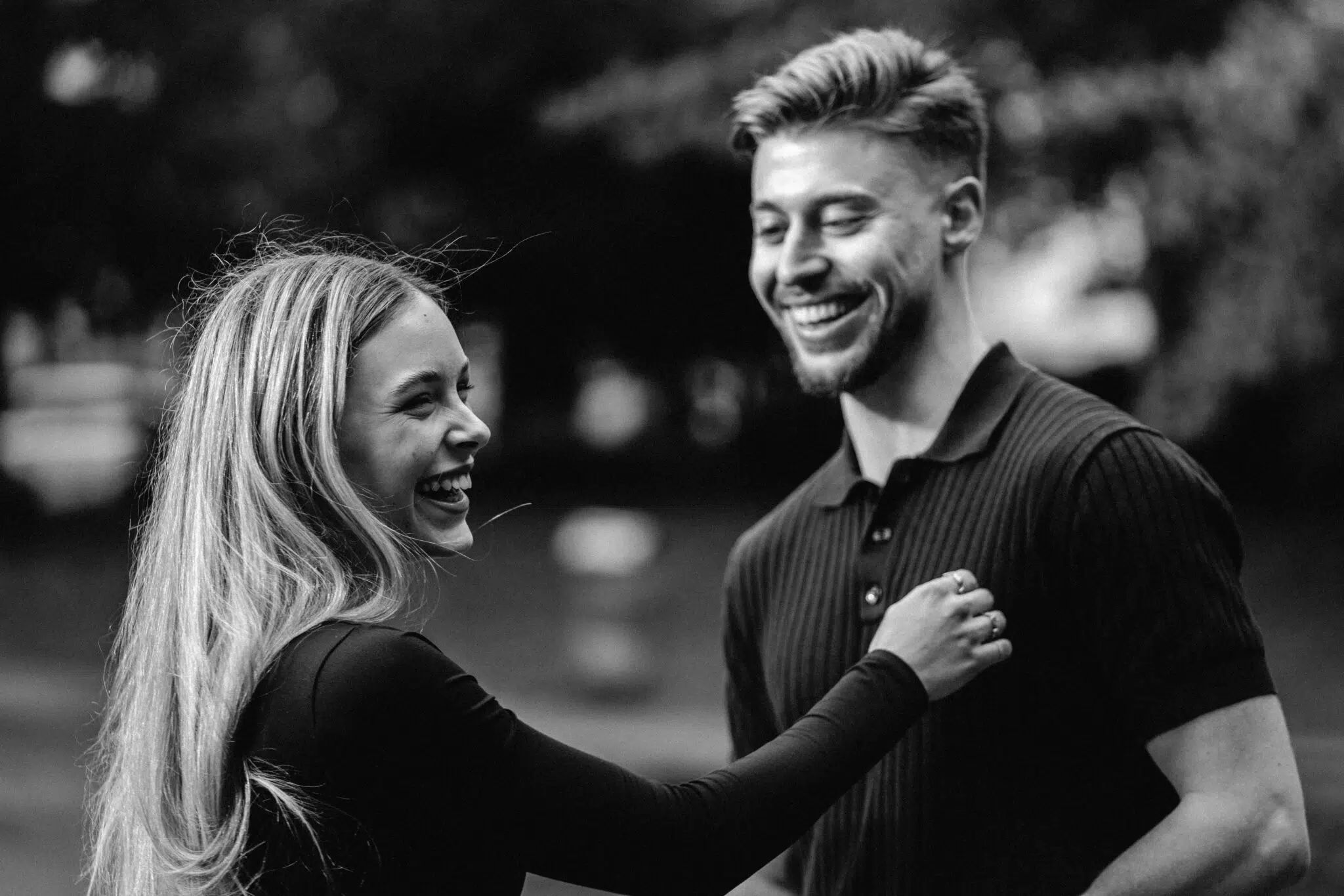 Fröhliches Paar lacht im Park. Mann und Frau genießen Zeit. Schwarzweißfoto, Glück