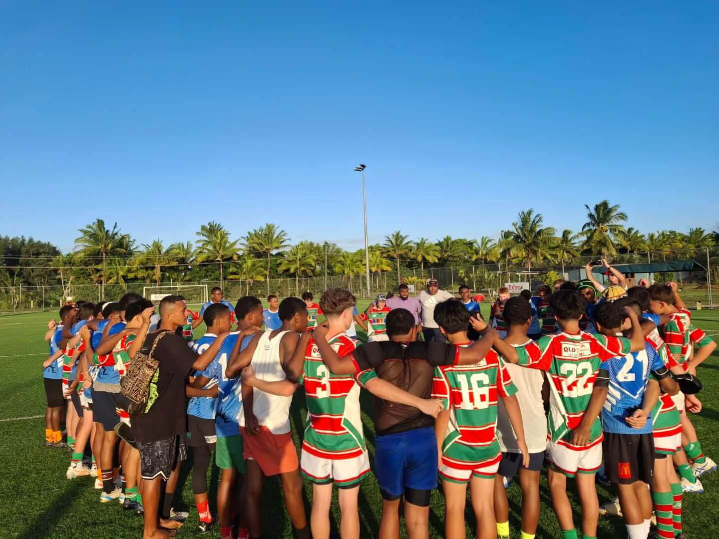 a sports team huddles together around each other - arms around one another teamwork