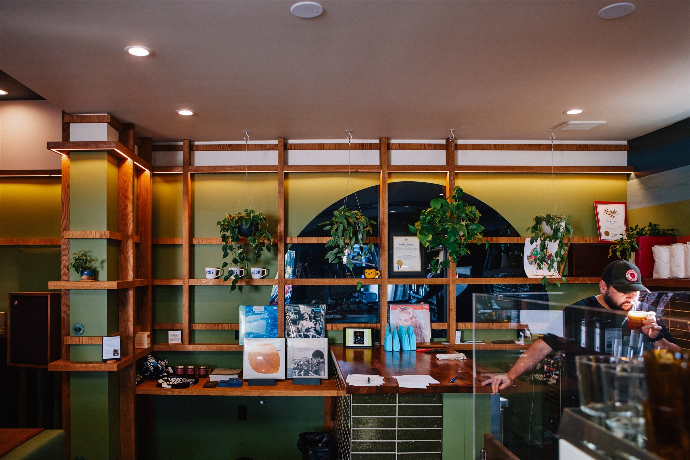 Timber shelving, records and green wall panels behind the Dedo Coffee counter