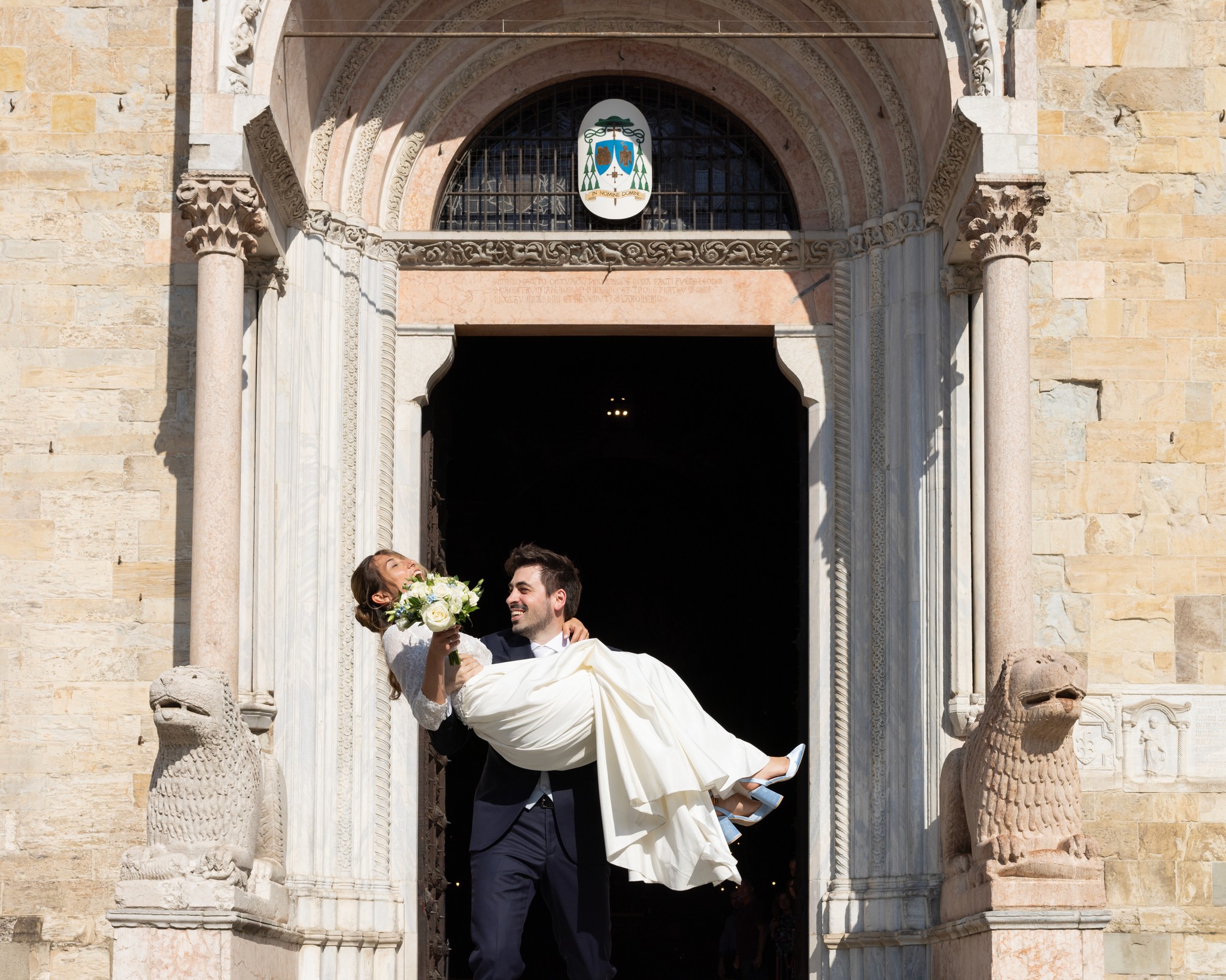 Sposo solleva sposa davanti al portale di Villa Peroni Riva, gesto leggero e spontaneo nel reportage di matrimonio
