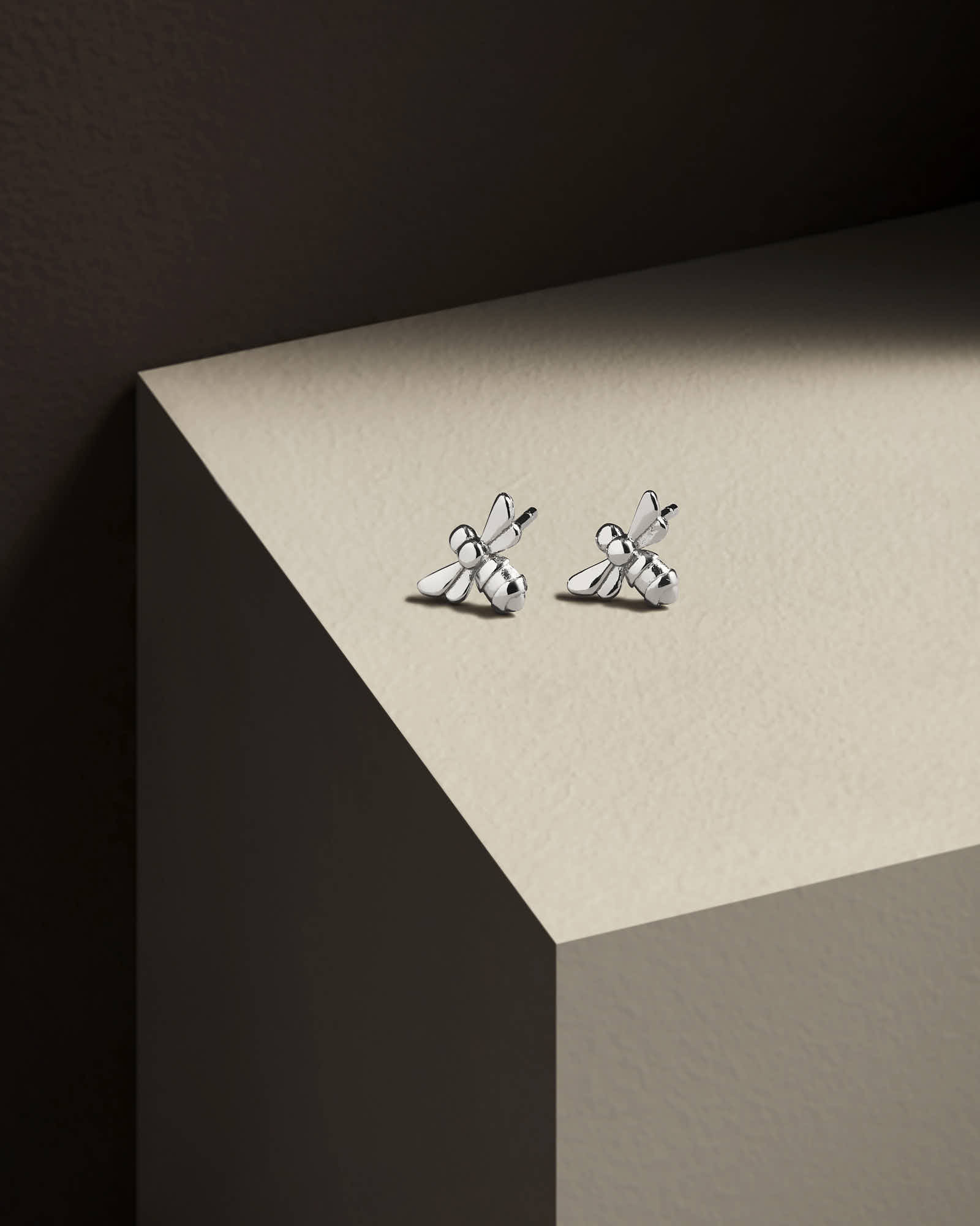 Abstract shot of a corner surface with delicate, minimalist earrings resting on it.
