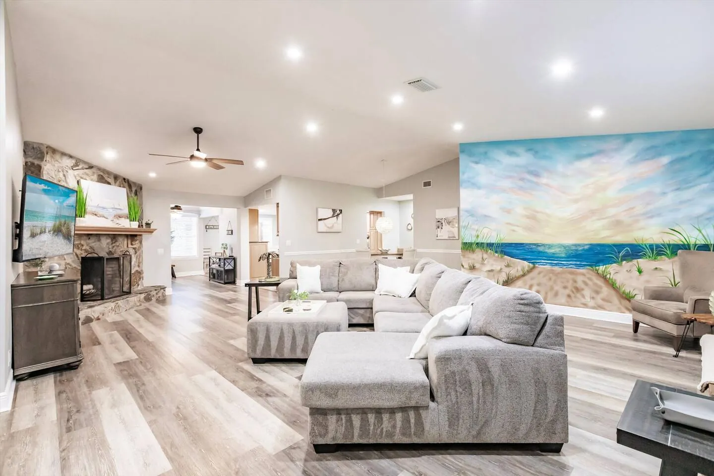 Living room with sectional, beach mural and fireplace at Sarasota Beach Bungalow, Bradenton, Florida