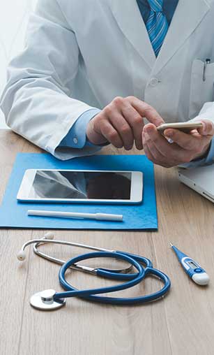 A smiling woman doctor is sitting at her desk and looking at a computer screen showing a medical screening test.