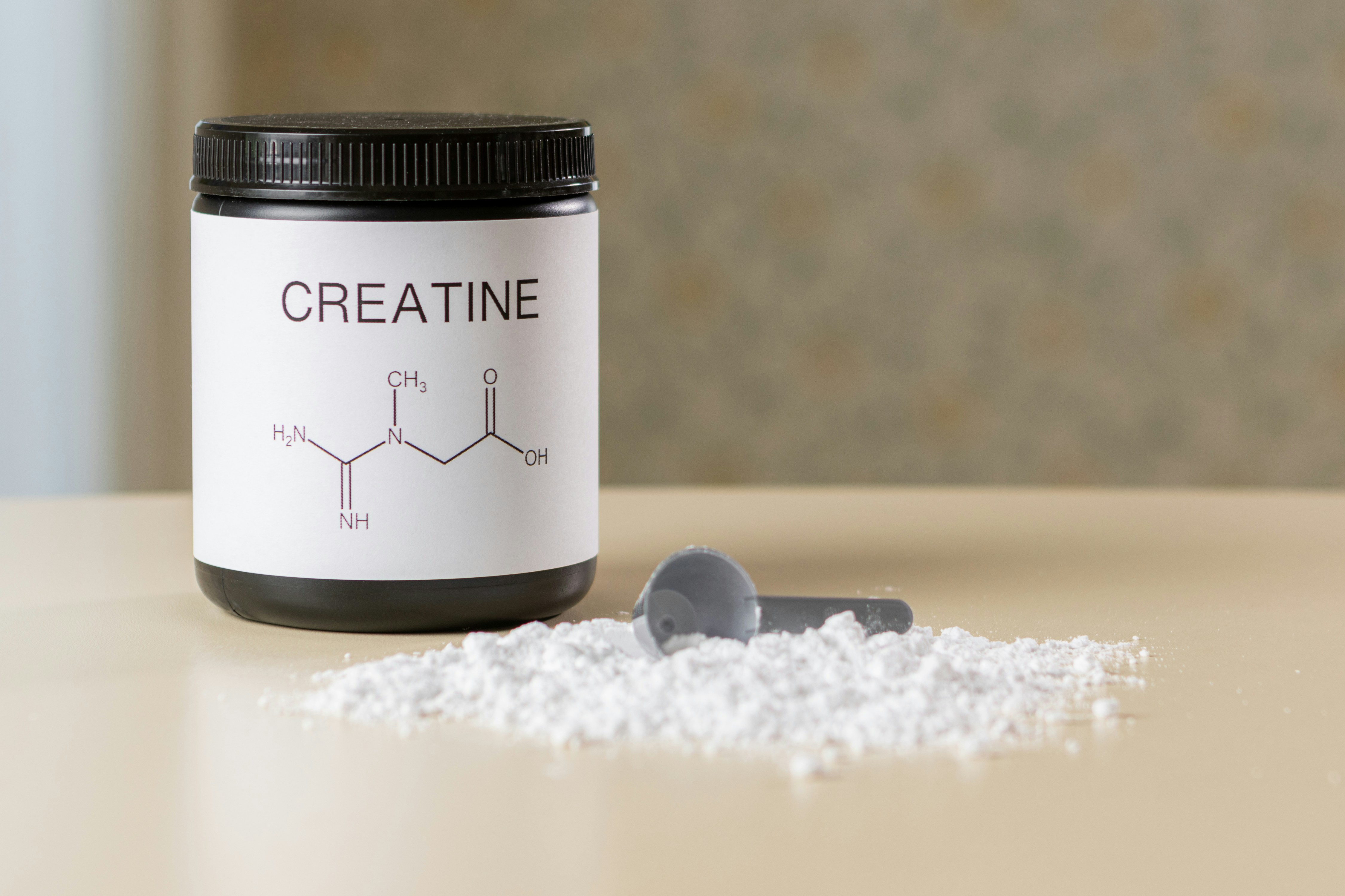 Creatine Container and Scoop with creatine laid out on a table