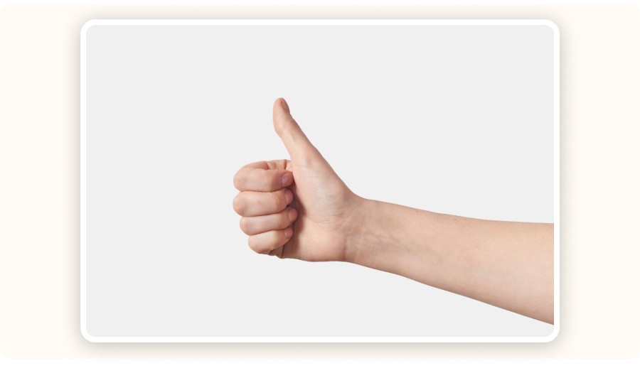 Hand showing thumbs up gesture on neutral background, symbol of approval&nbsp;