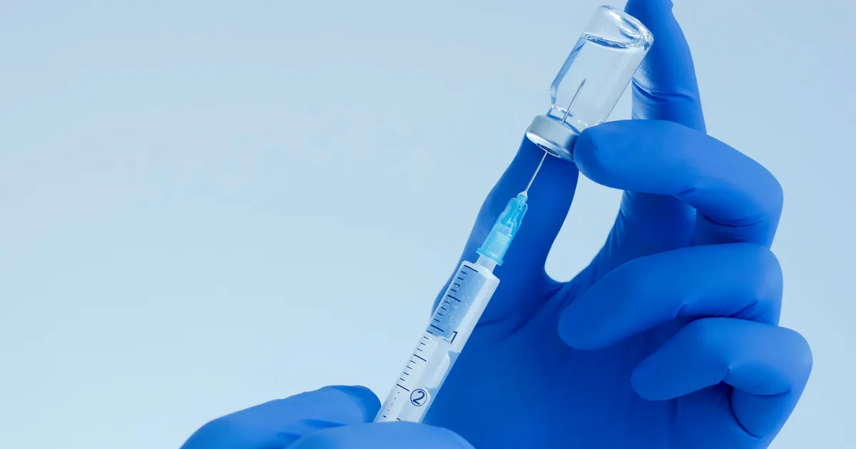 Doctor hands holding a vaccine bottle and syringe.