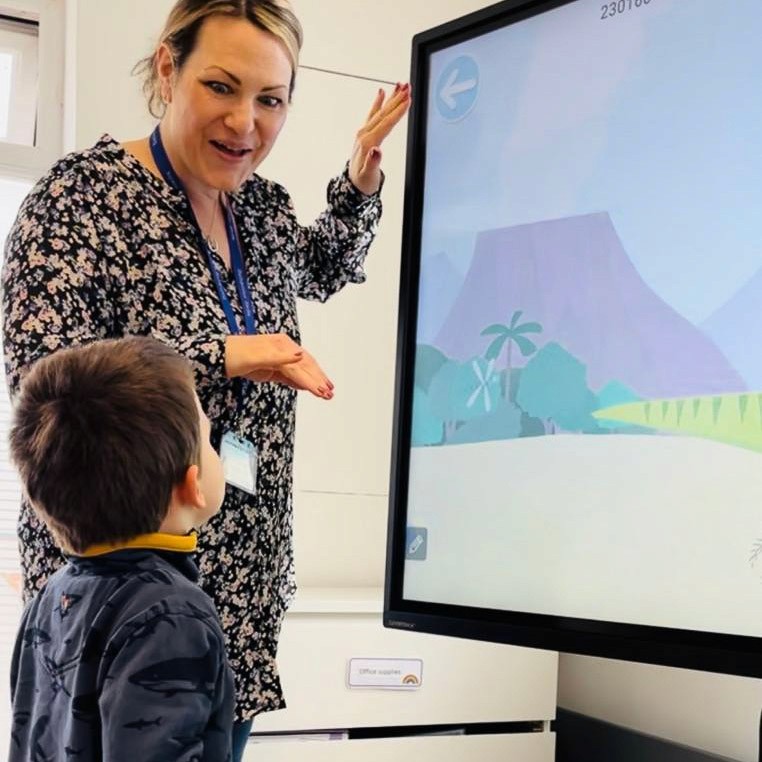 A Horizon Hub team member is showing one of the children images of a volcano on a digital whiteboard