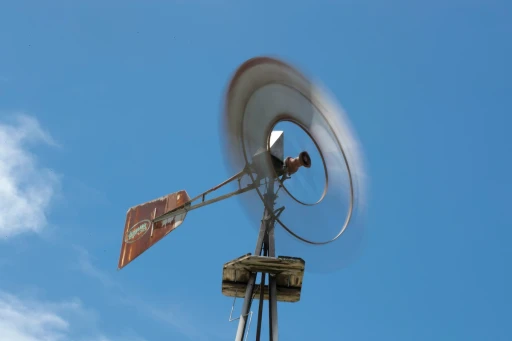 Spinning windmill against a clear blue sky on a windy day.