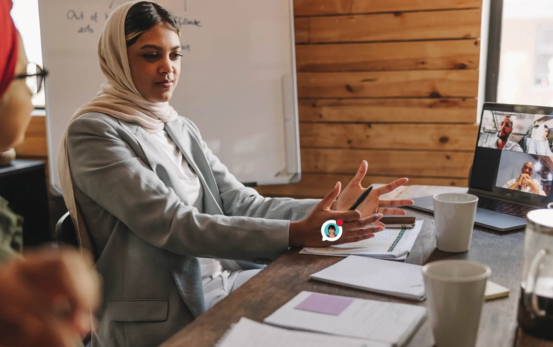 Healthcare professional in a hybrid meeting connecting with remote colleagues via video call on a laptop, illustrating cross-sector collaboration