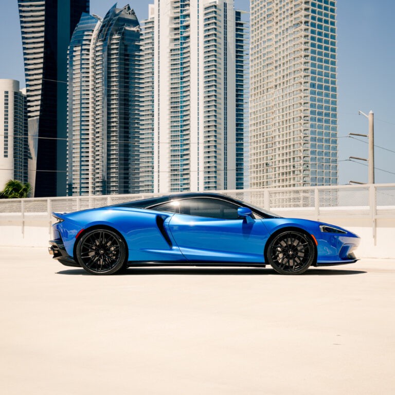 Side profile of a blue McLaren GT, showcasing its sleek lines and grand tourer silhouette.