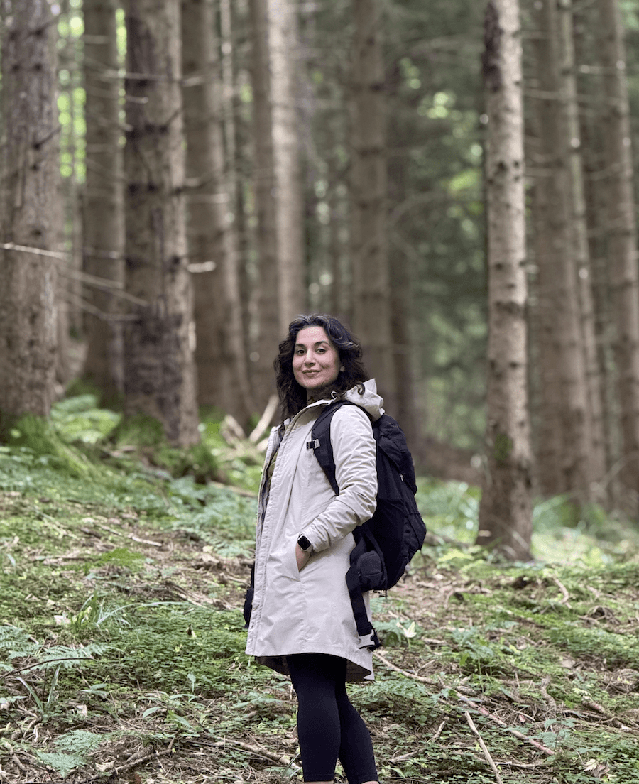 A young person with long, wavy hair sits in front of a plain background, looking directly at the camera.