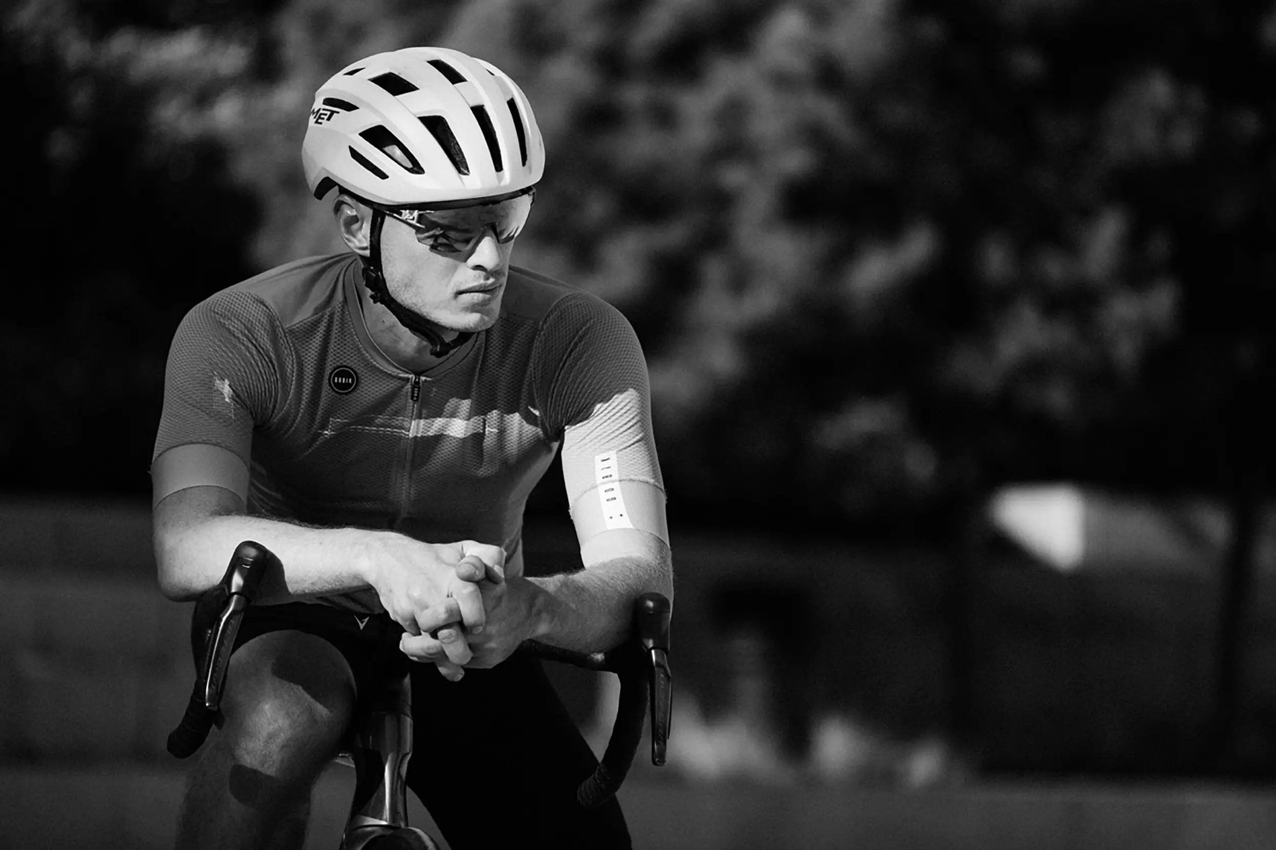 Ironman training tips in action — focused cyclist in aero position with race nutrition taped to his arm during a triathlon bike training session