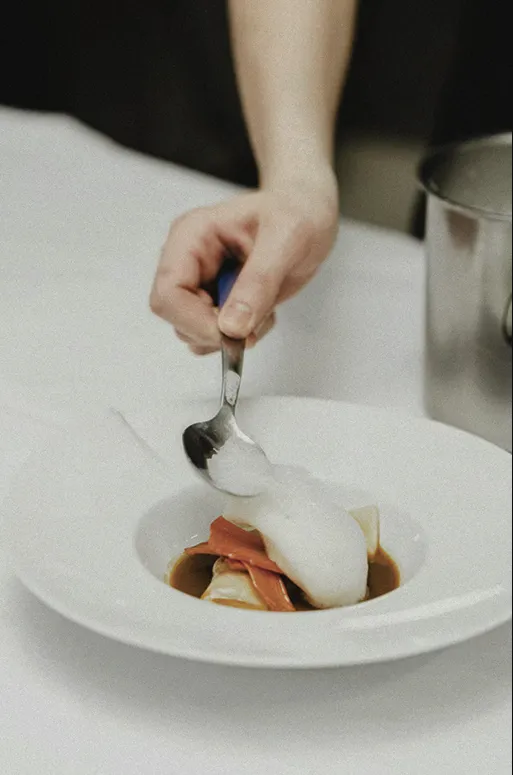 A chef delicately plating a gourmet dish, adding a fine foam topping — capturing artistry, precision, and modern French cuisine at its best.  