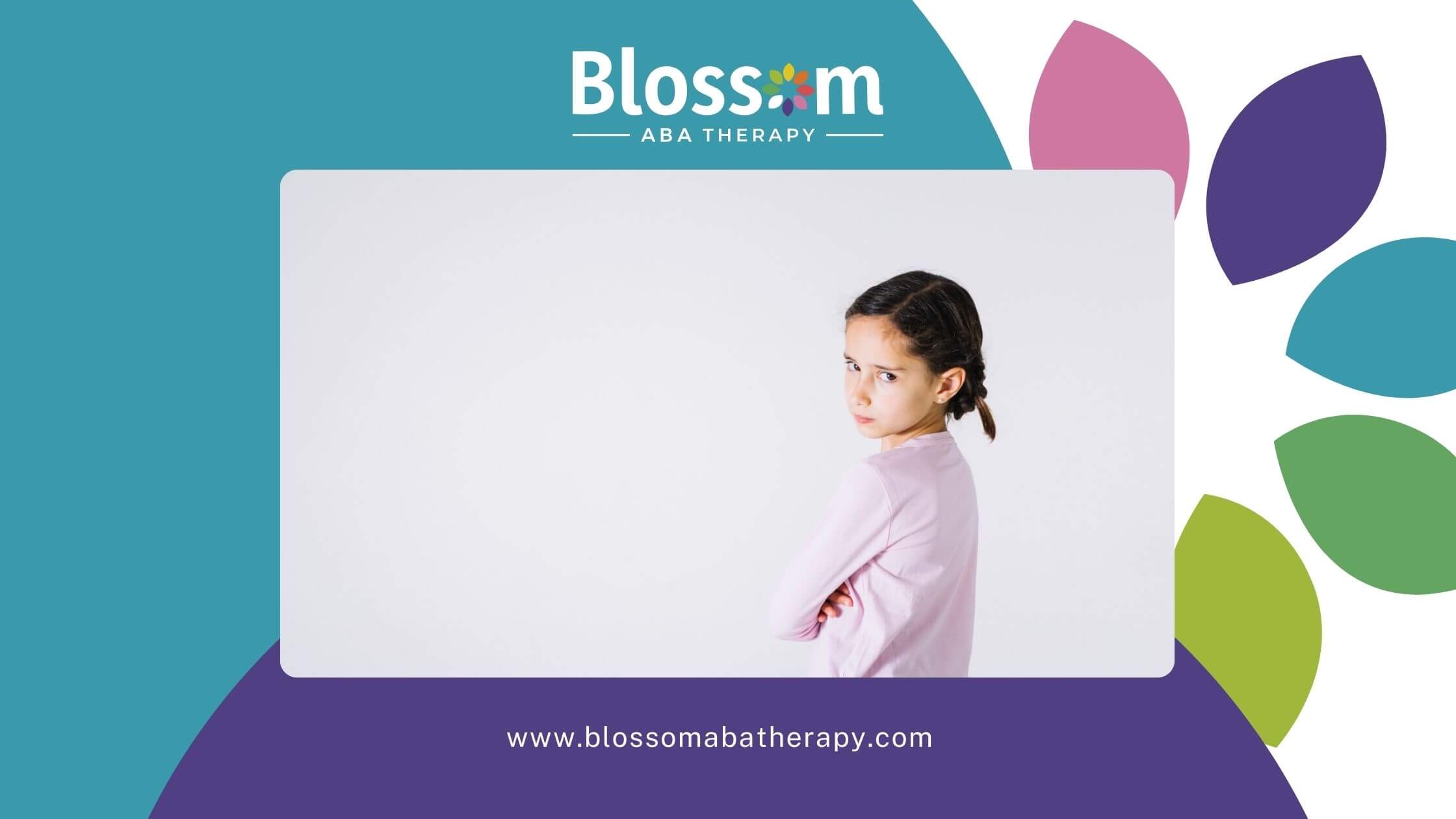 An autistic girl with braided hair, looking upset and standing with her arms crossed.