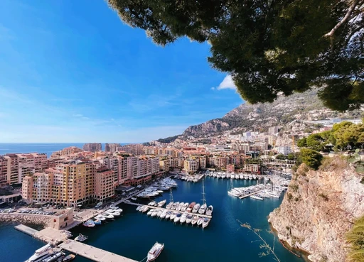 Panoramic view of a Mediterranean harbor with luxury yachts and rocky cliffs on the French Riviera