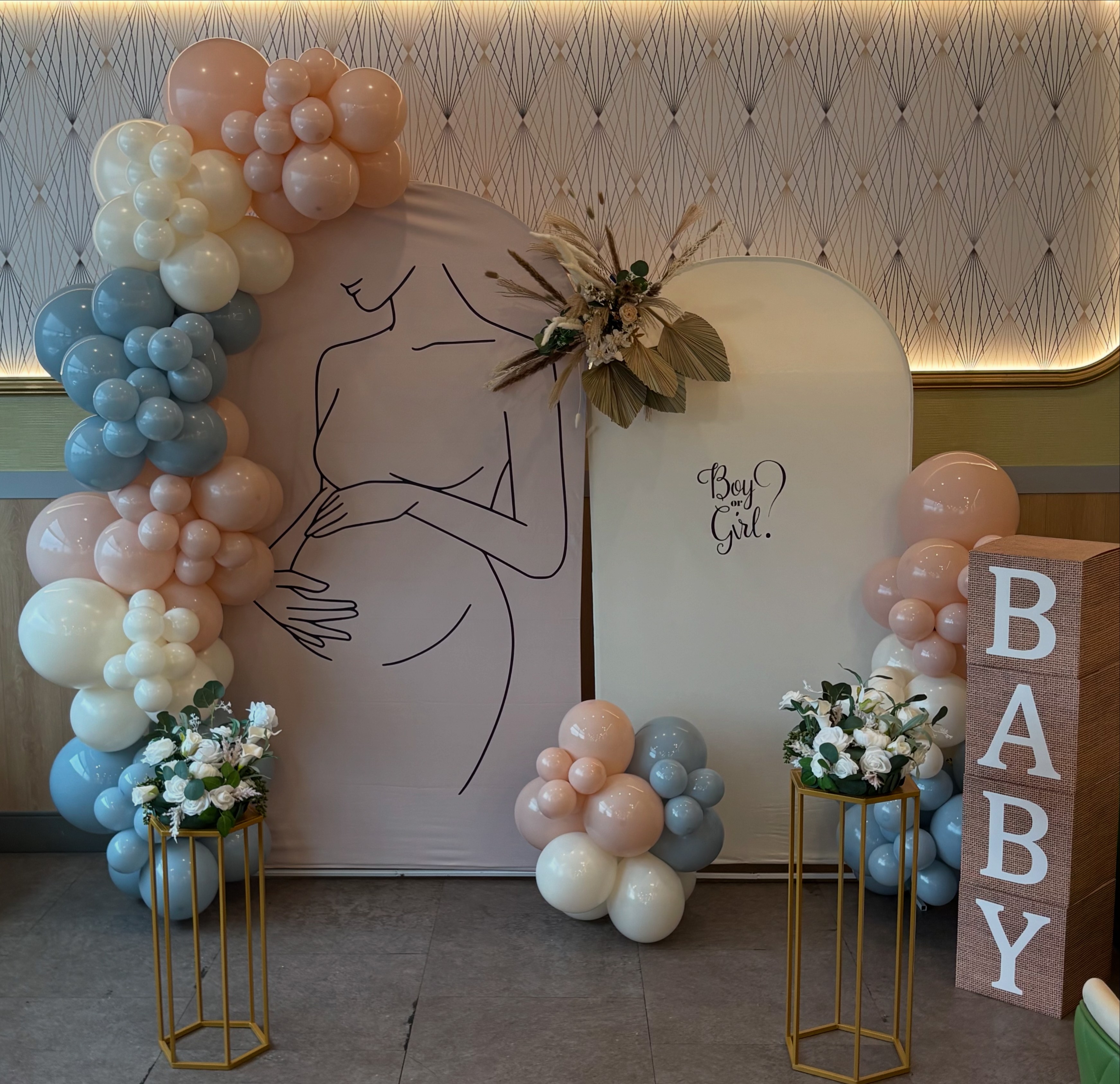 Nude, Brown and white balloon arch in a office. There is a cake stand and a dusty pink arch behind it.