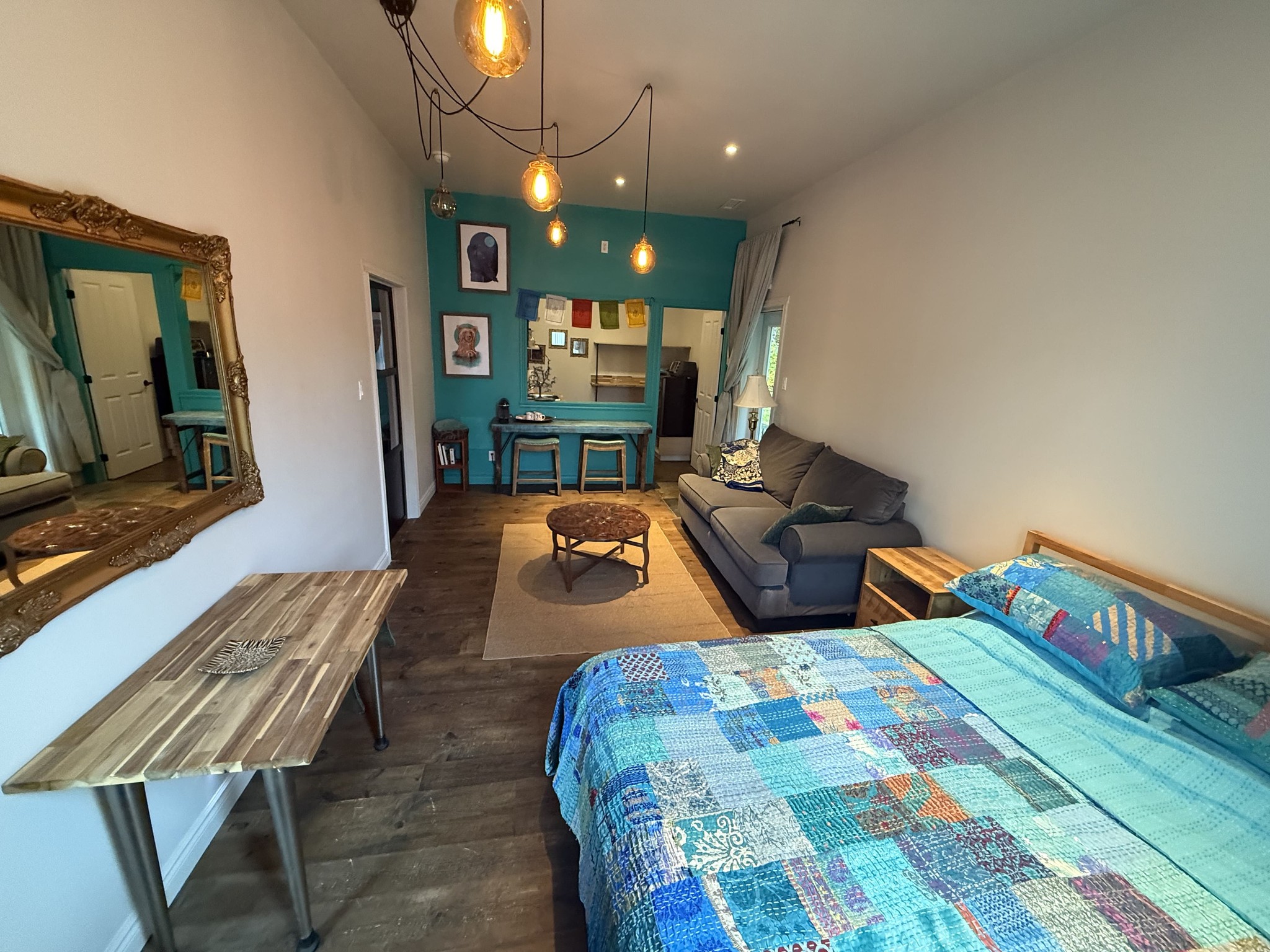 Grande pièce ouverte combinant chambre, salon et coin café, déco éclectique et ambiance chaleureuse.