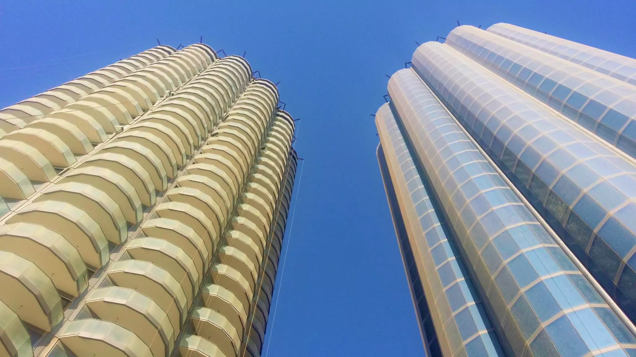 Looking up at the impressive curved balconies and glass structure of these luxury Dubai towers.
