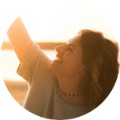 Sarah, 45, smiling with arms raised outdoors during golden hour sunset
