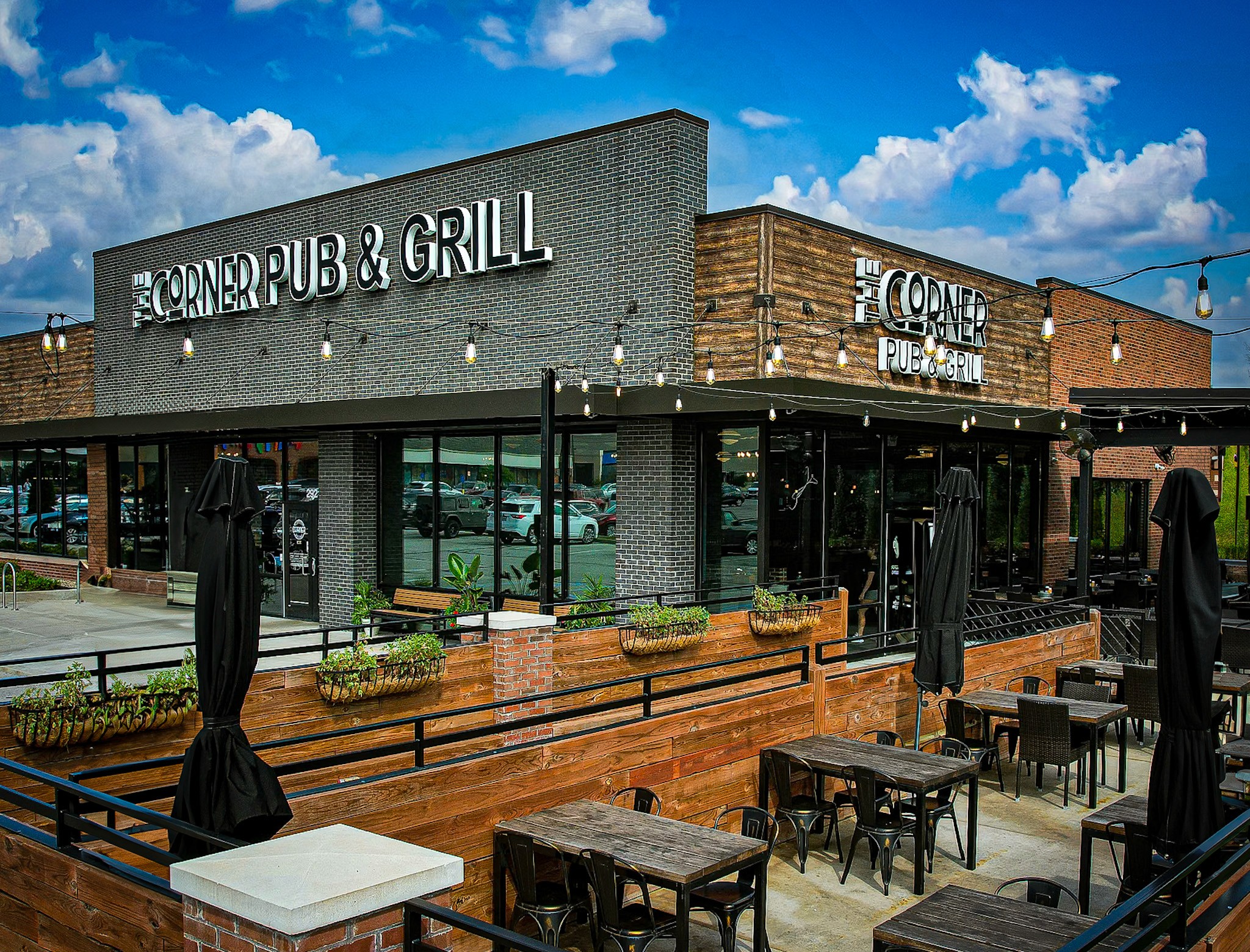 A modern restaurant exterior with seating outside, under a blue sky with scattered clouds.