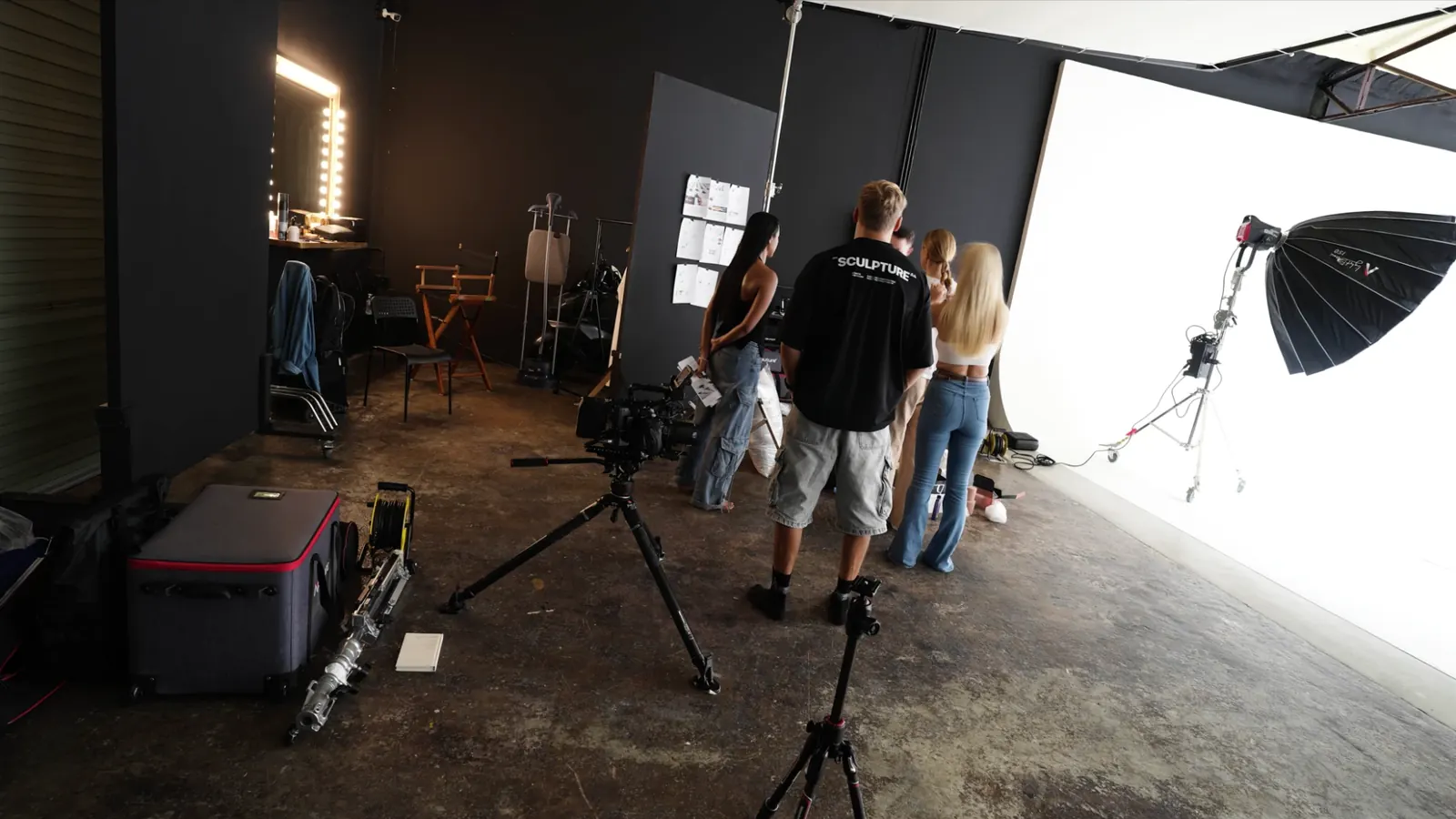 Crew reviewing the storyboard pinned to the wall next to the white cyclorama