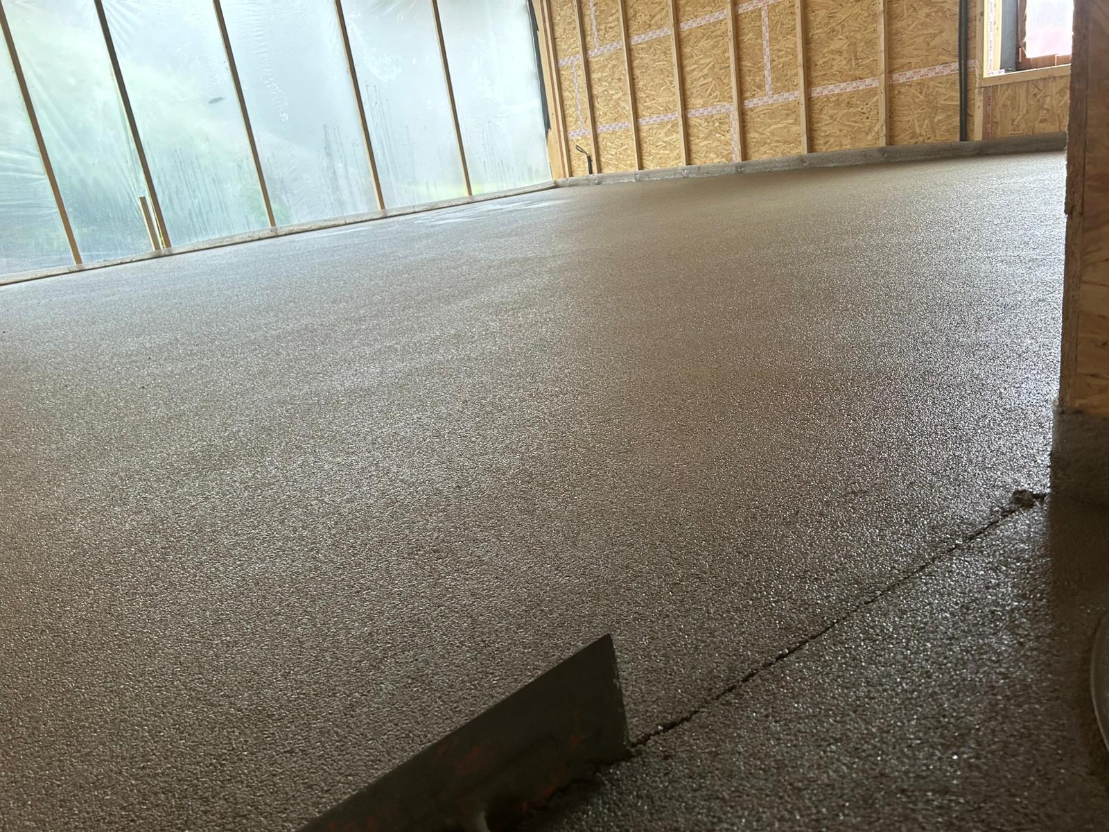 Frisch gegossener Betonboden mit Kelle, bereit für Bau- oder Renovierungsarbeiten.

