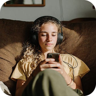 A teenager with headphones on her smartphone.