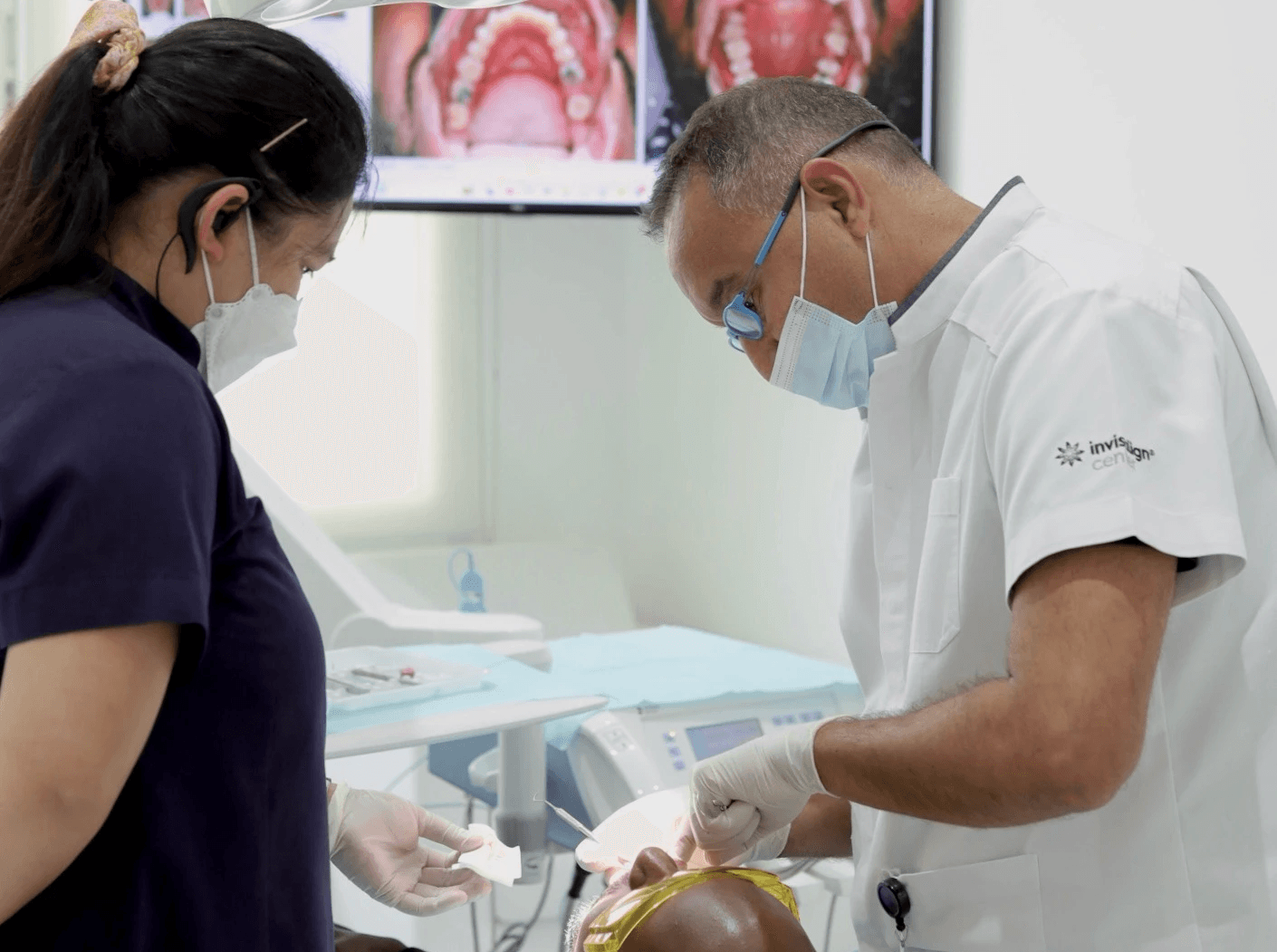 A dentist and an assistant examining a patient’s teeth in preparation for having a teeth retainer by Invisalign Center