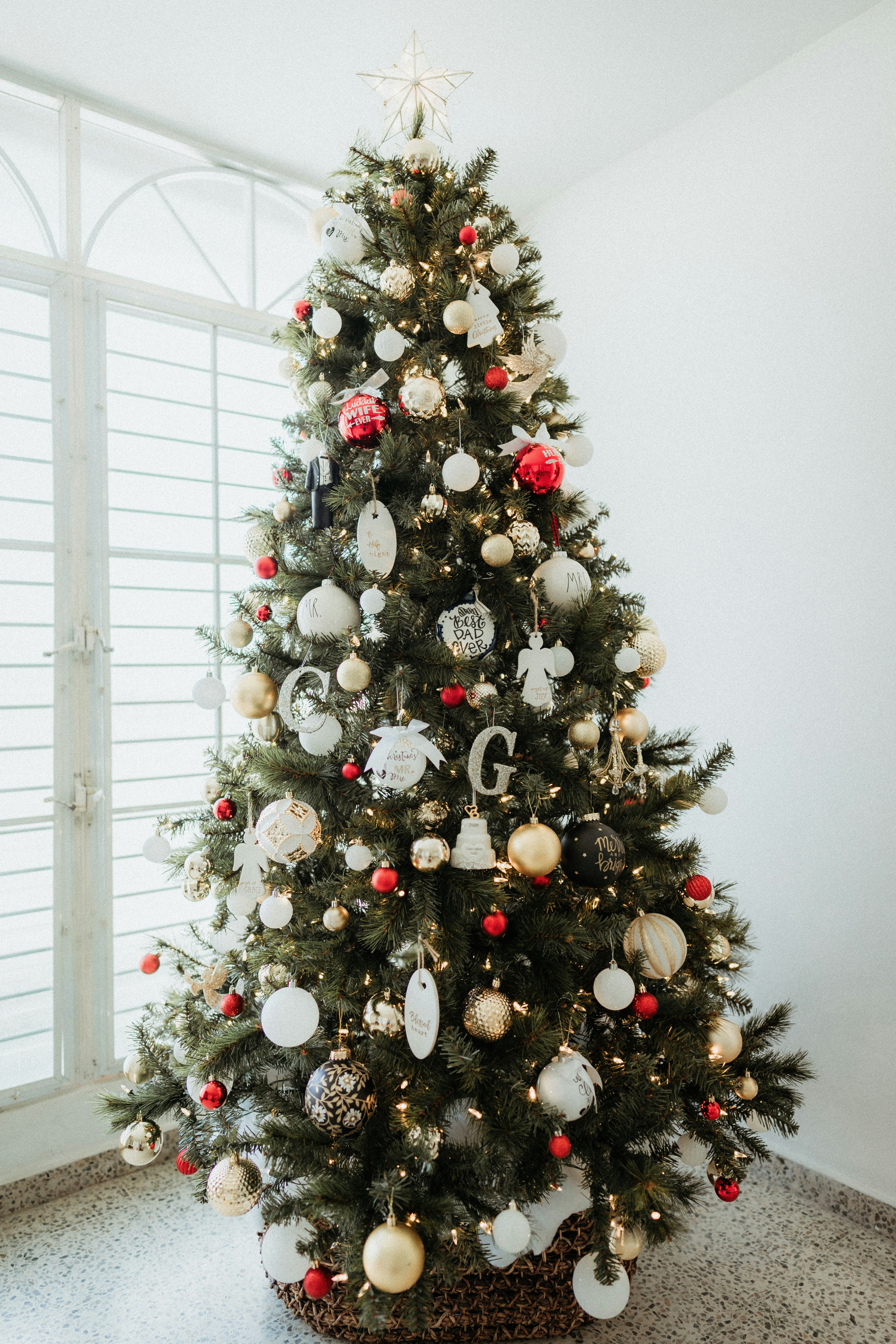 A decorated Christmas tree up against the window.