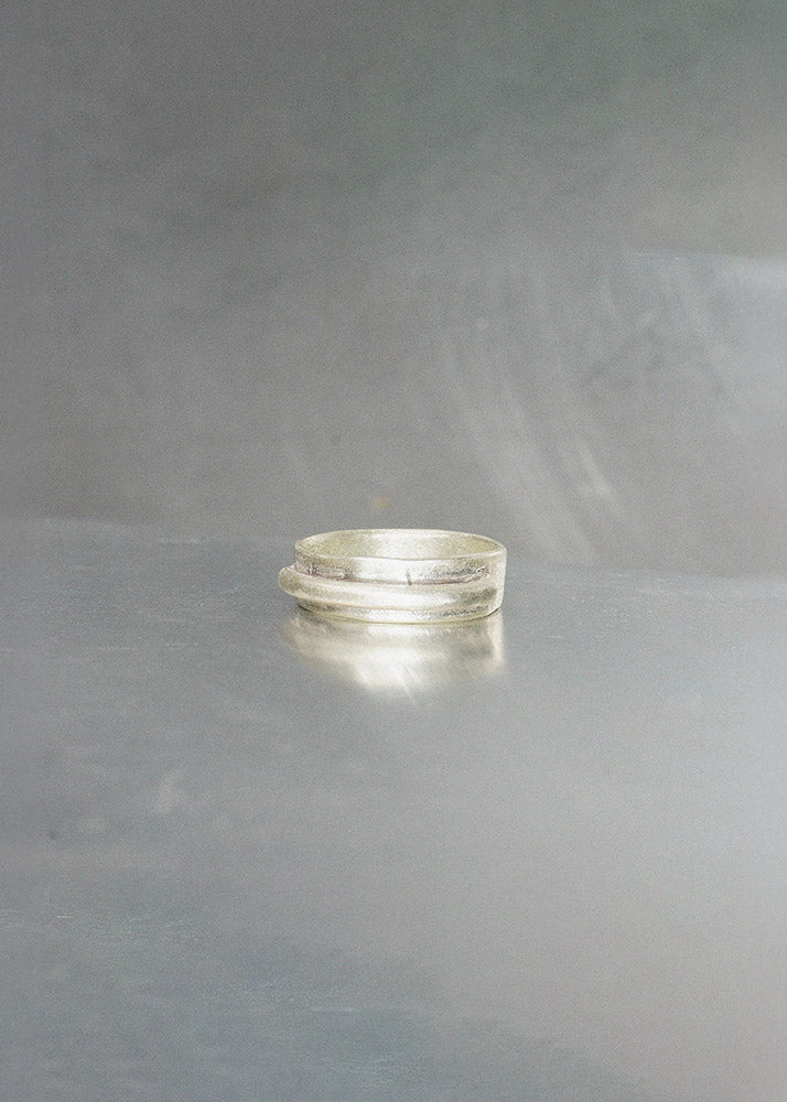 Stack of silver rings on a gray surface with a gray background