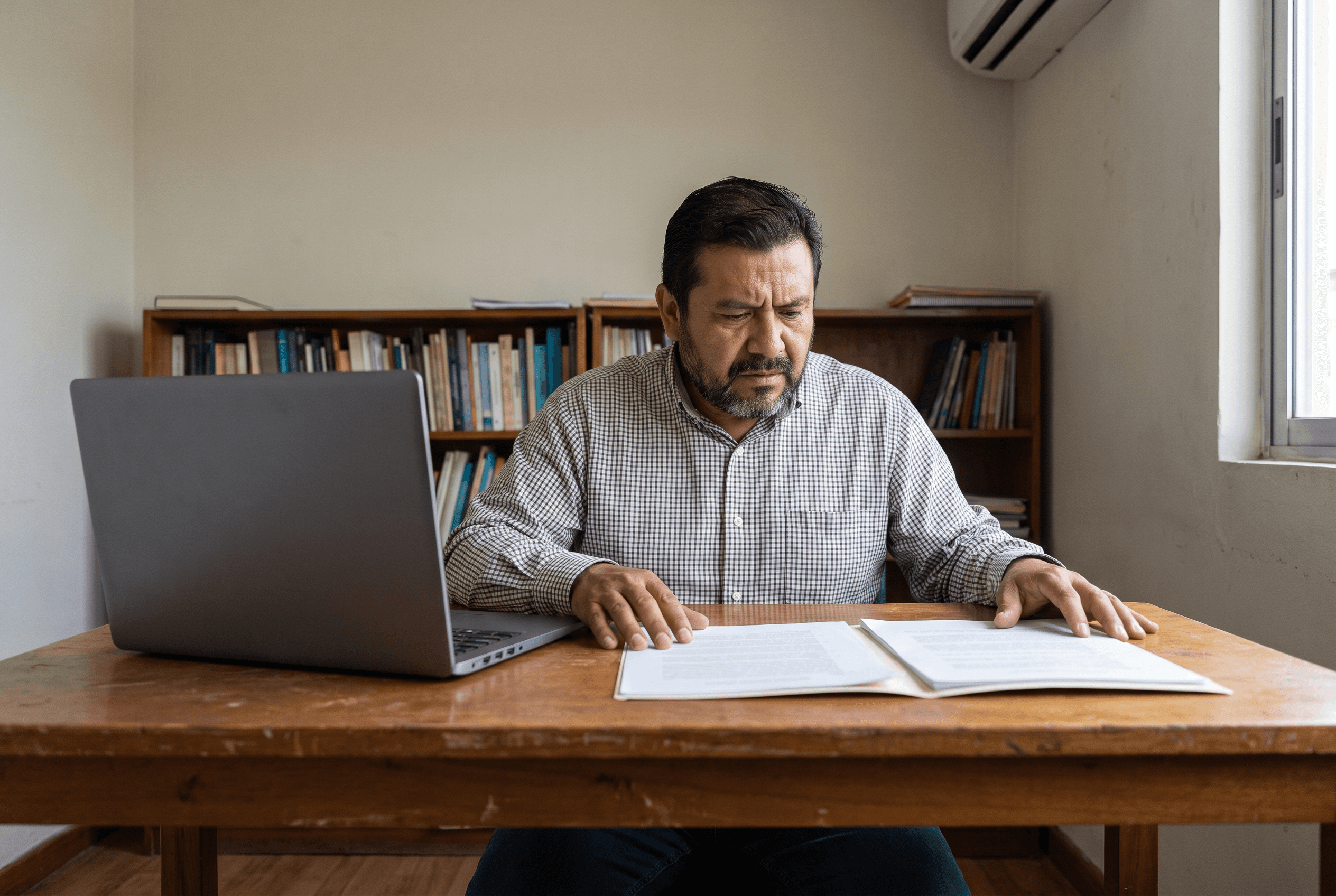 A business owner at his desk comparing two documents side by side