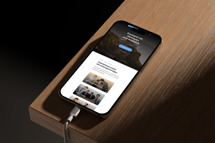 Mockup eines iPhones auf einem Holztisch mit geöffneter Advisa-Website. Auf dem Display ist die Startseite mit dem Claim ‚Treuhand mit Vertrauen und Weitblick‘ sowie Leistungsübersichten zu sehen.