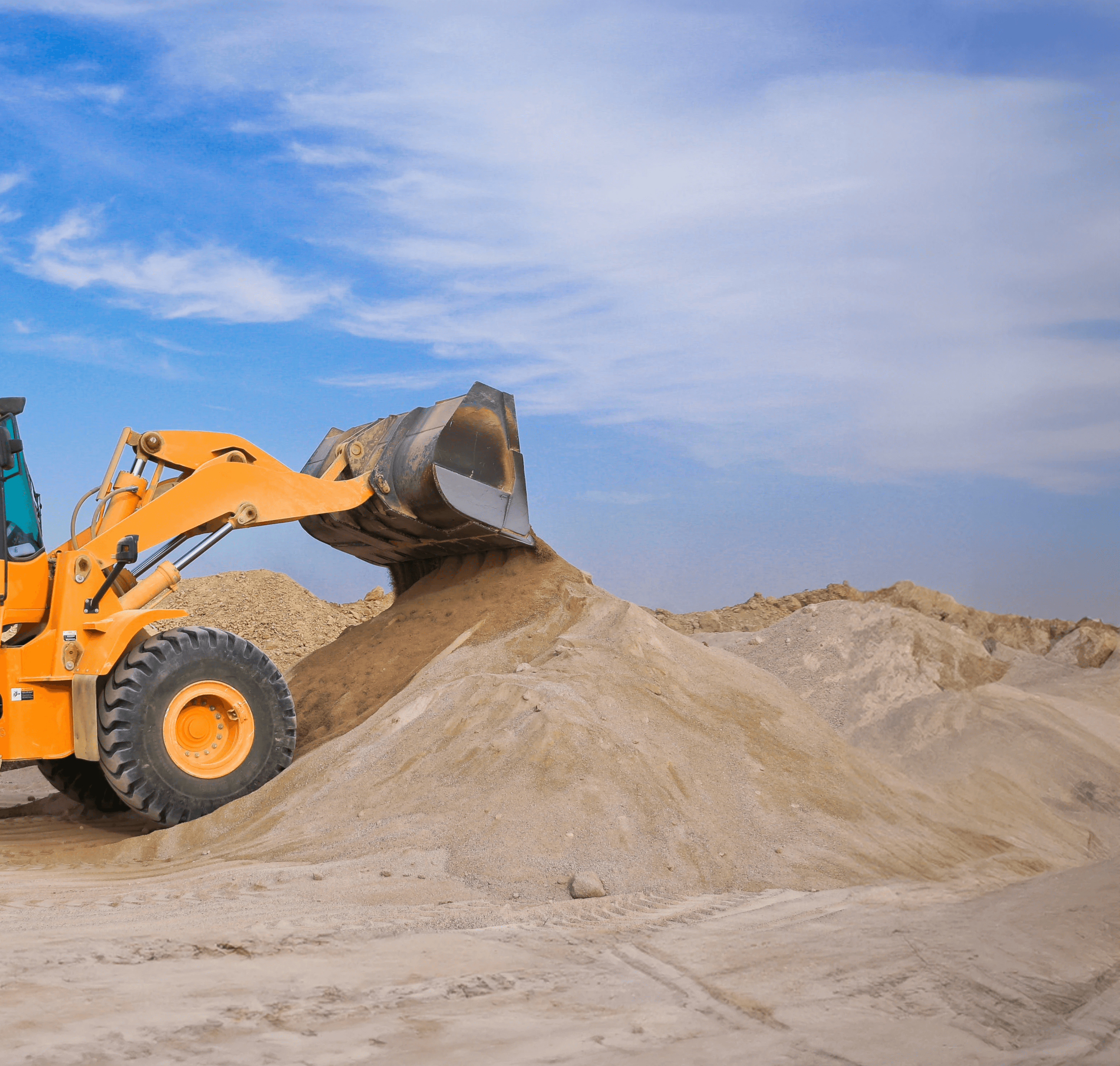 A loader dumping sand into a pile