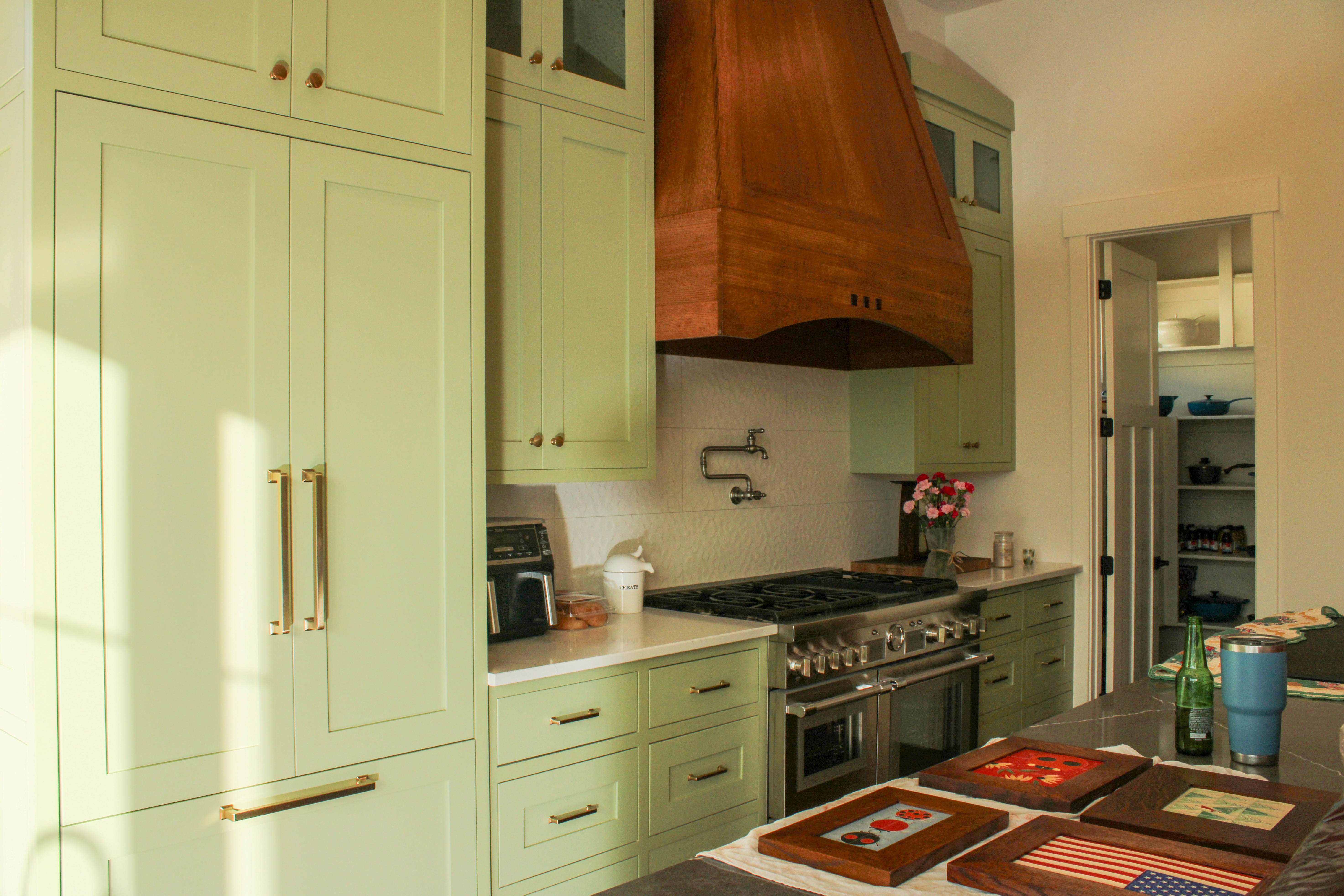 St. George Utah home kitchen highlighting green cabinetry, natural wood island, and retro-modern design with a natural wood custom hood.