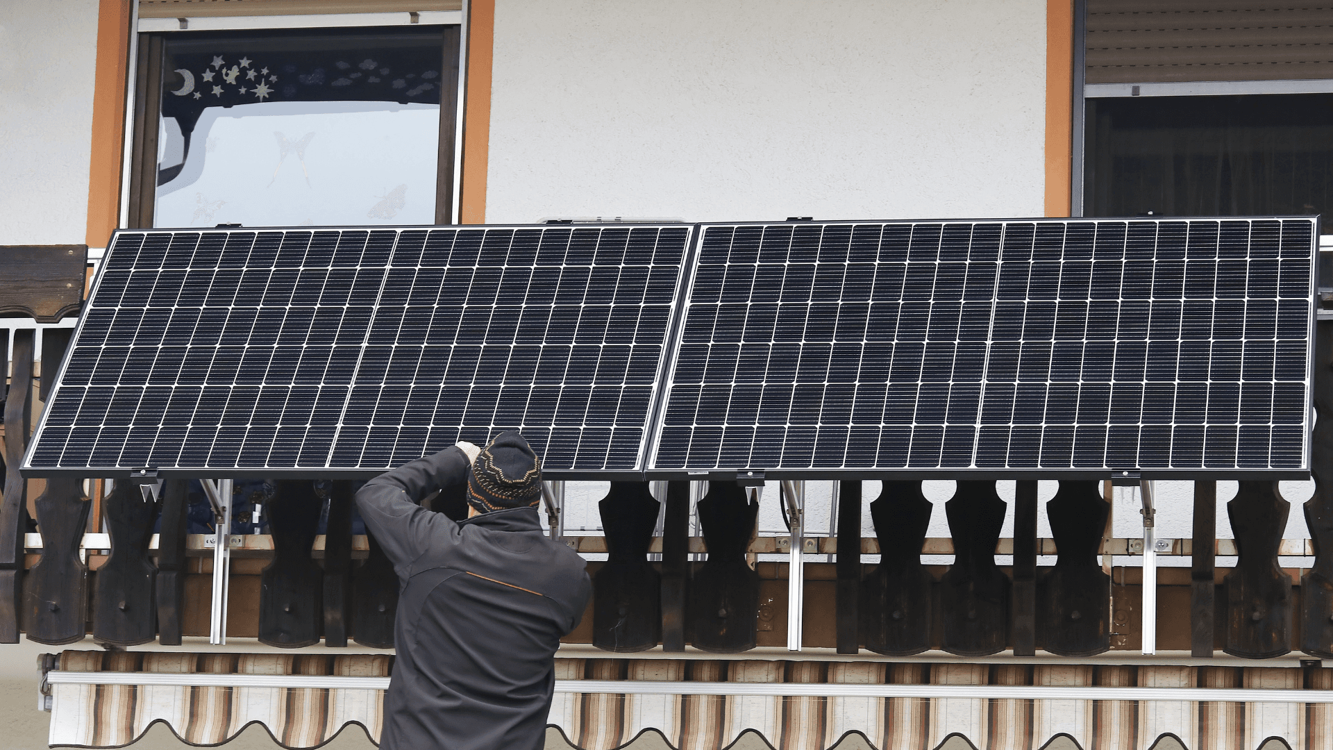 Eine Person richtet Solarpaneele auf dem Dach eines Gebäudes aus oder installiert sie.
