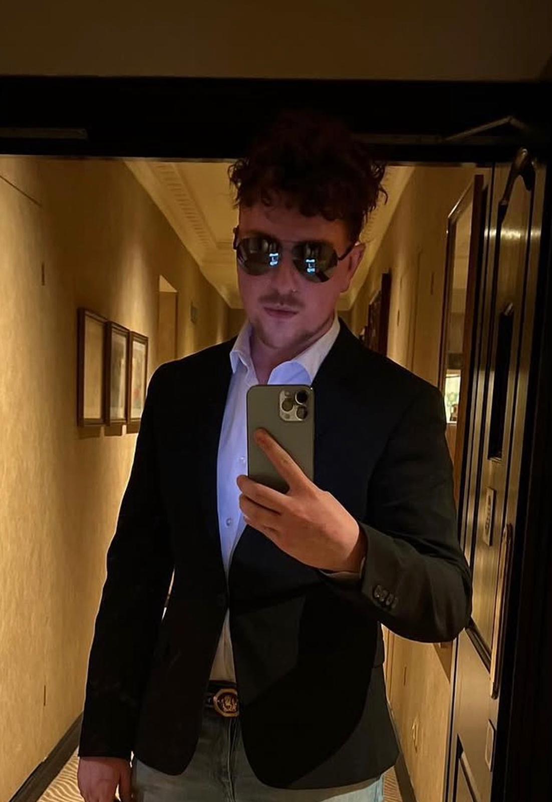 A young man in a coat smiling by looking infront