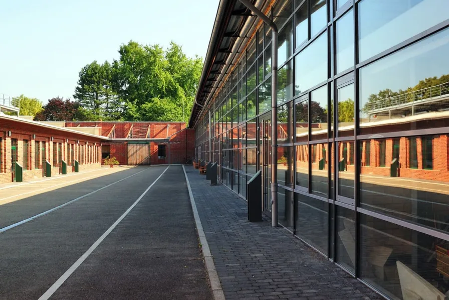 Leerer Innenhof zwischen Backstein-Industriegebäuden mit einer langen Glasfassade