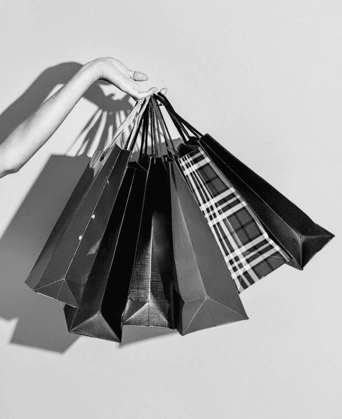 A smiling young man with crossed arms, wearing a plaid shirt and white t-shirt, poses against a dark background.