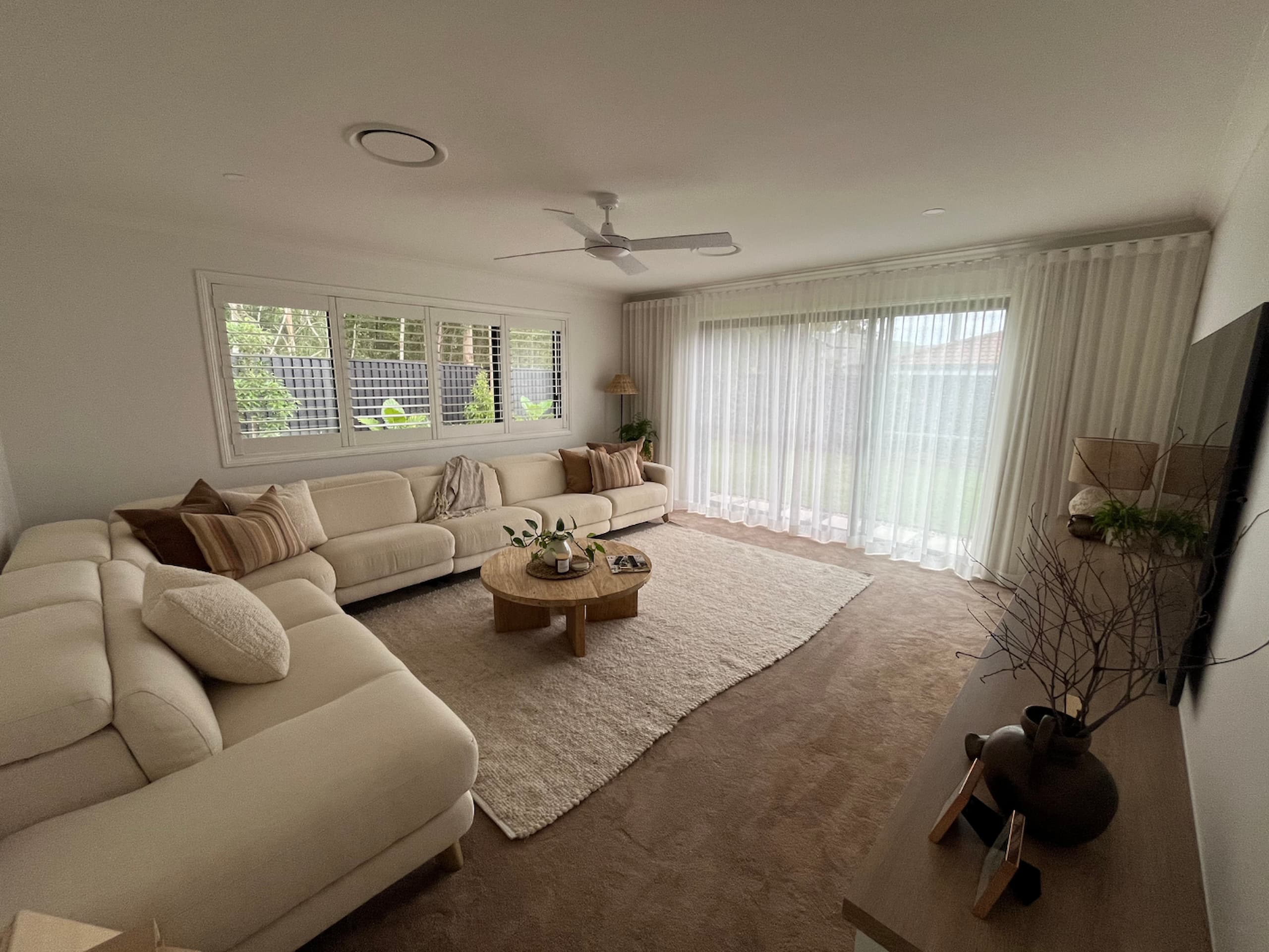 Spacious living room with a large sectional sofa and natural light in a renovated Brisbane home.