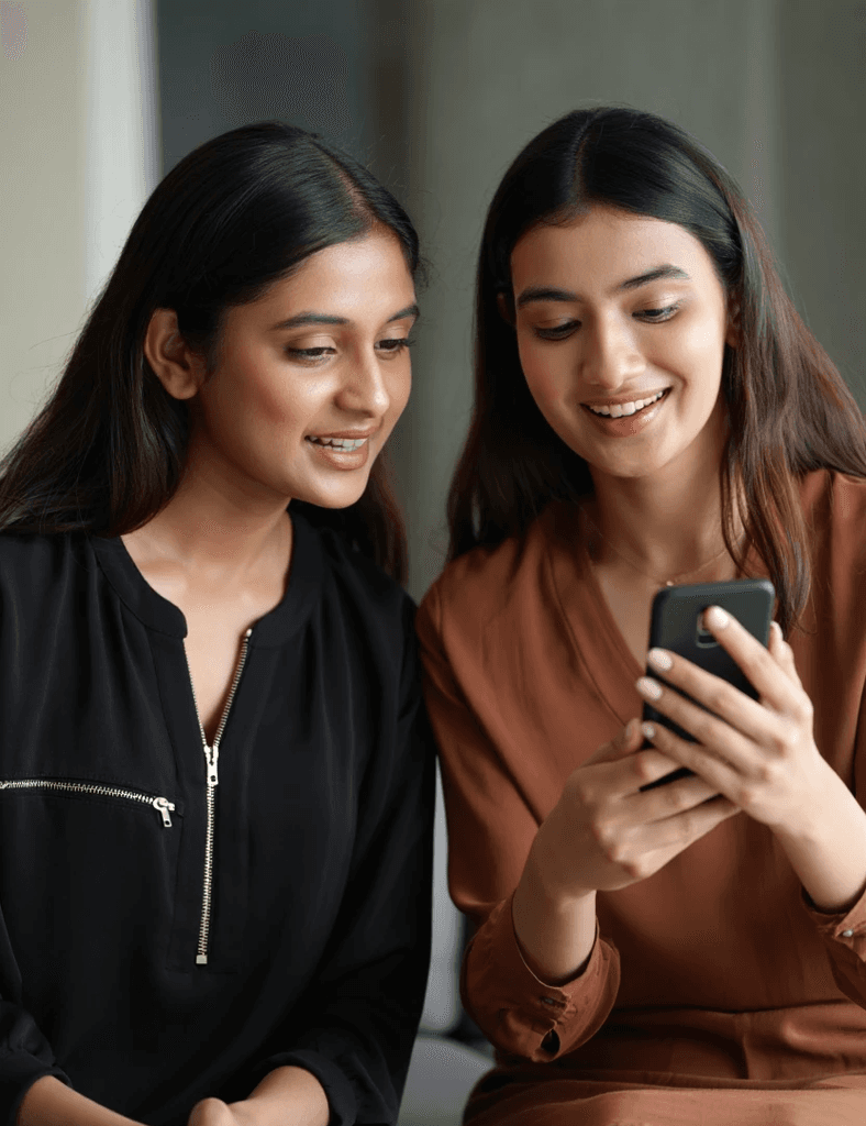 Two women looking at a phone and receiving notifications for three accepted invites and ₹1000 earned from affiliate program of Quicko.