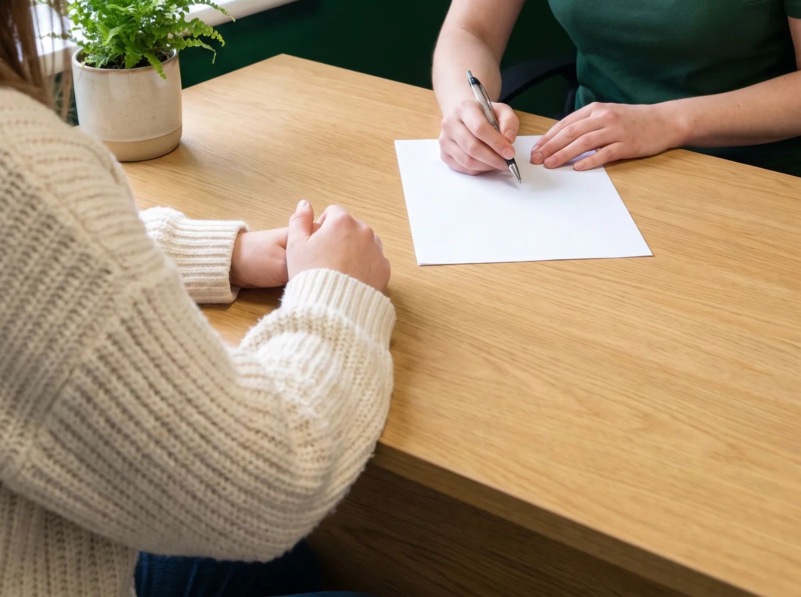 A pharmacist talking with a patient across a desk in a consultation room