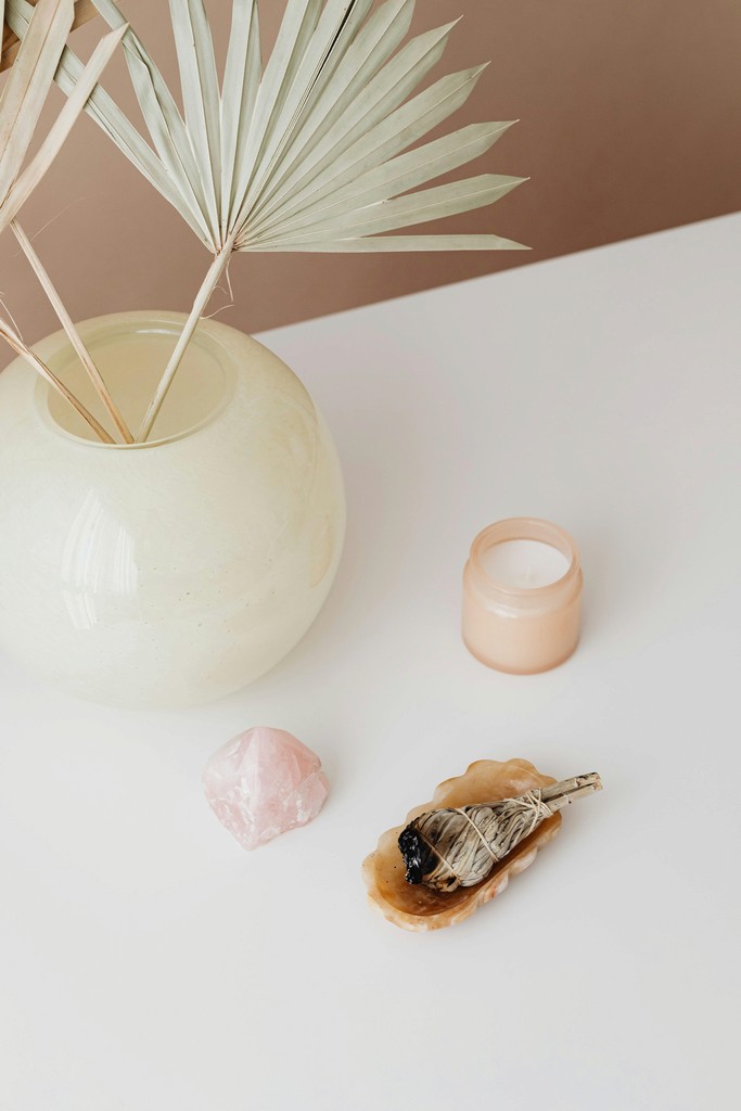 A woman lying on a massage bed, illuminated by soft sunlight streaming through a nearby window. A lush green plant in the background enhances the peaceful and rejuvenating ambiance.
