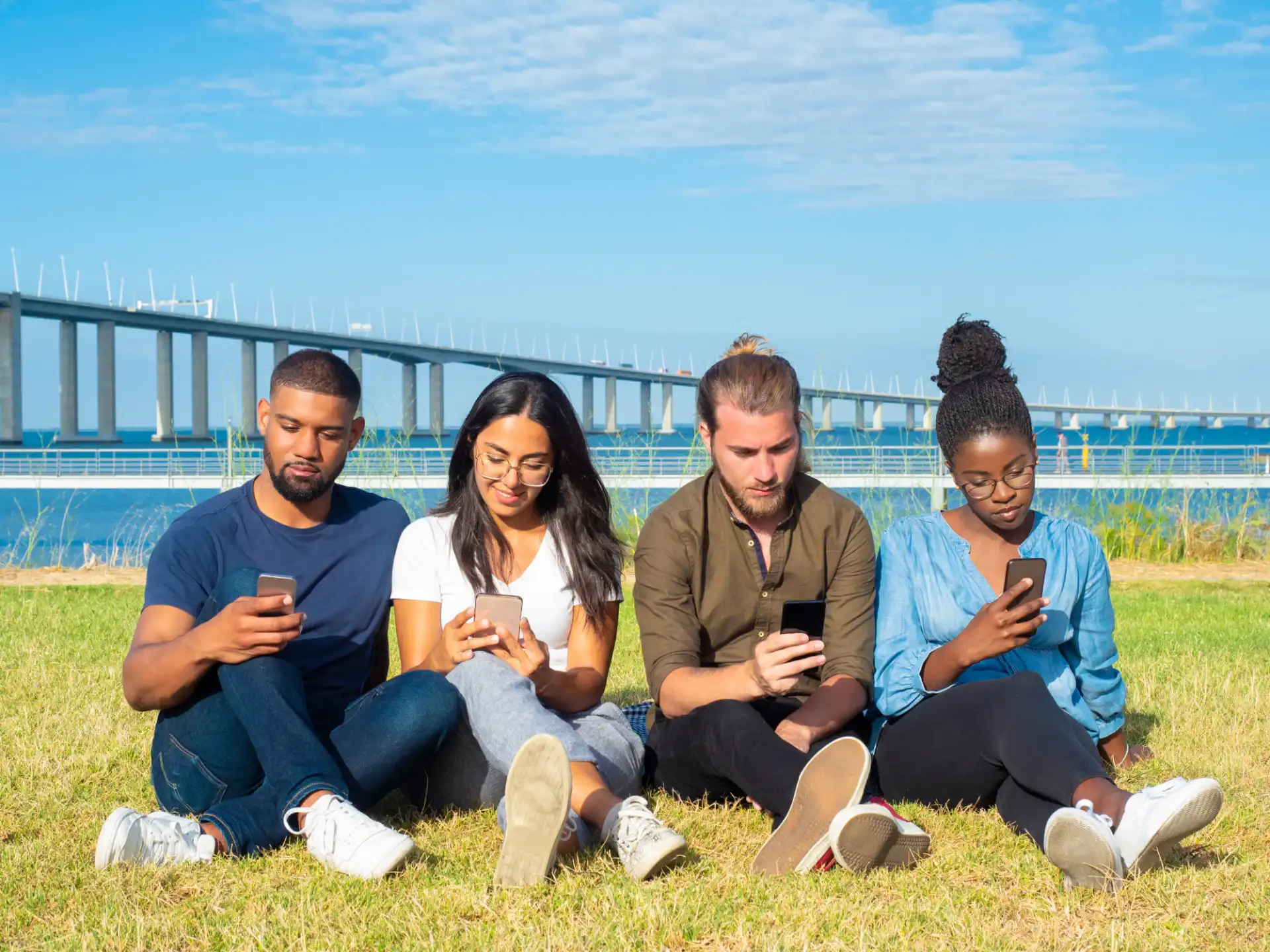 A group of young people sit outside, looking at their phones and engaging with new creator content on TikTok.