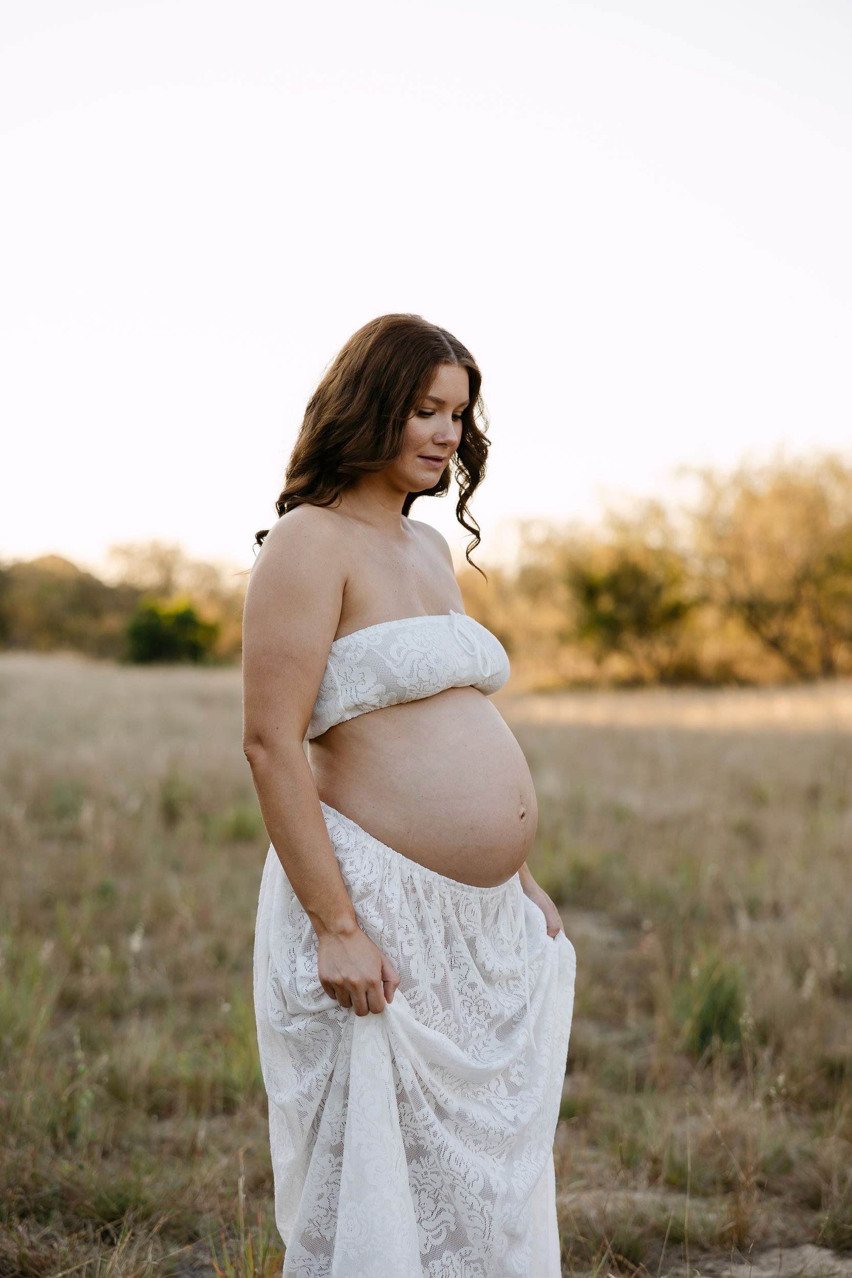 Pregnant mother standing in tall grass during maternity photo session Mackay