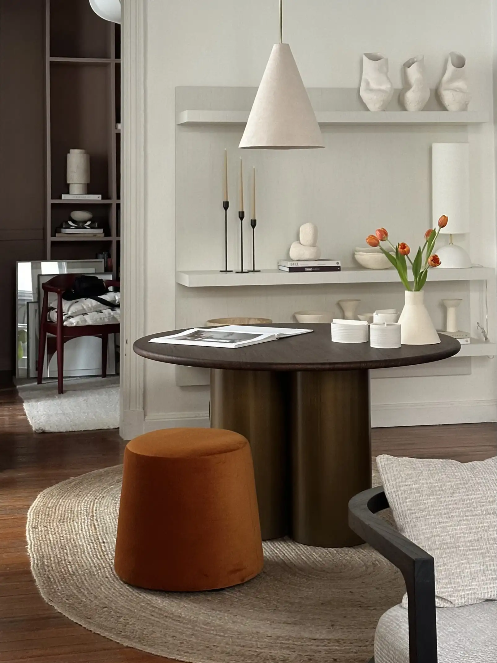 Espacio moderno con mesa redonda, florero de tulipanes y mobiliario neutro para estudios de interiorismo que muestran elegancia funcional.