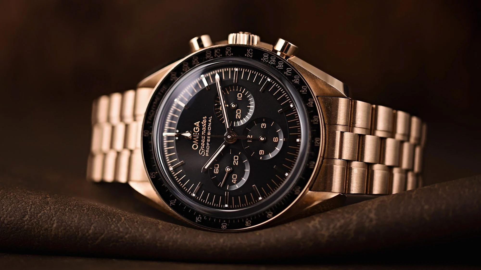 Gold Omega Speedmaster watch with black dial