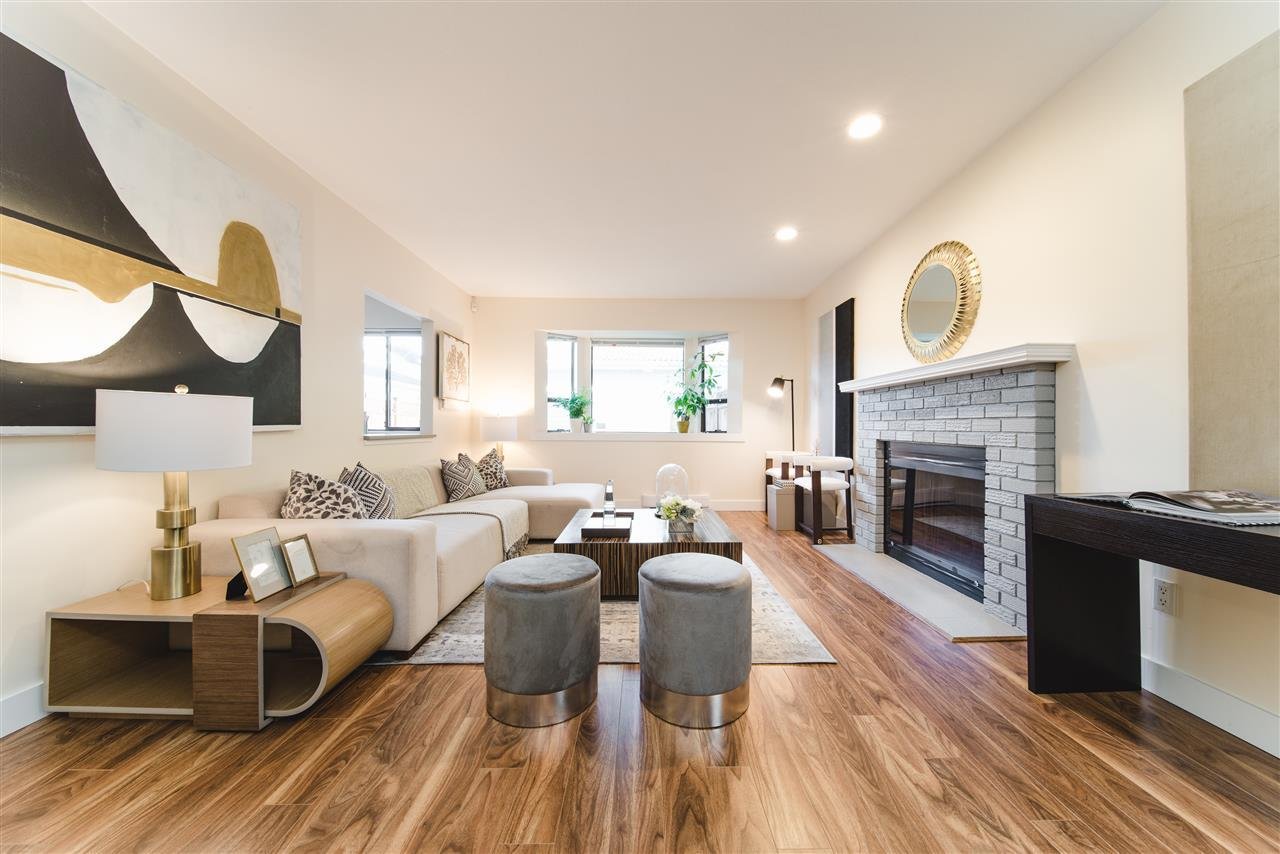 Modern living room featuring a fireplace, wooden floors, and stylish furniture with ample natural light.