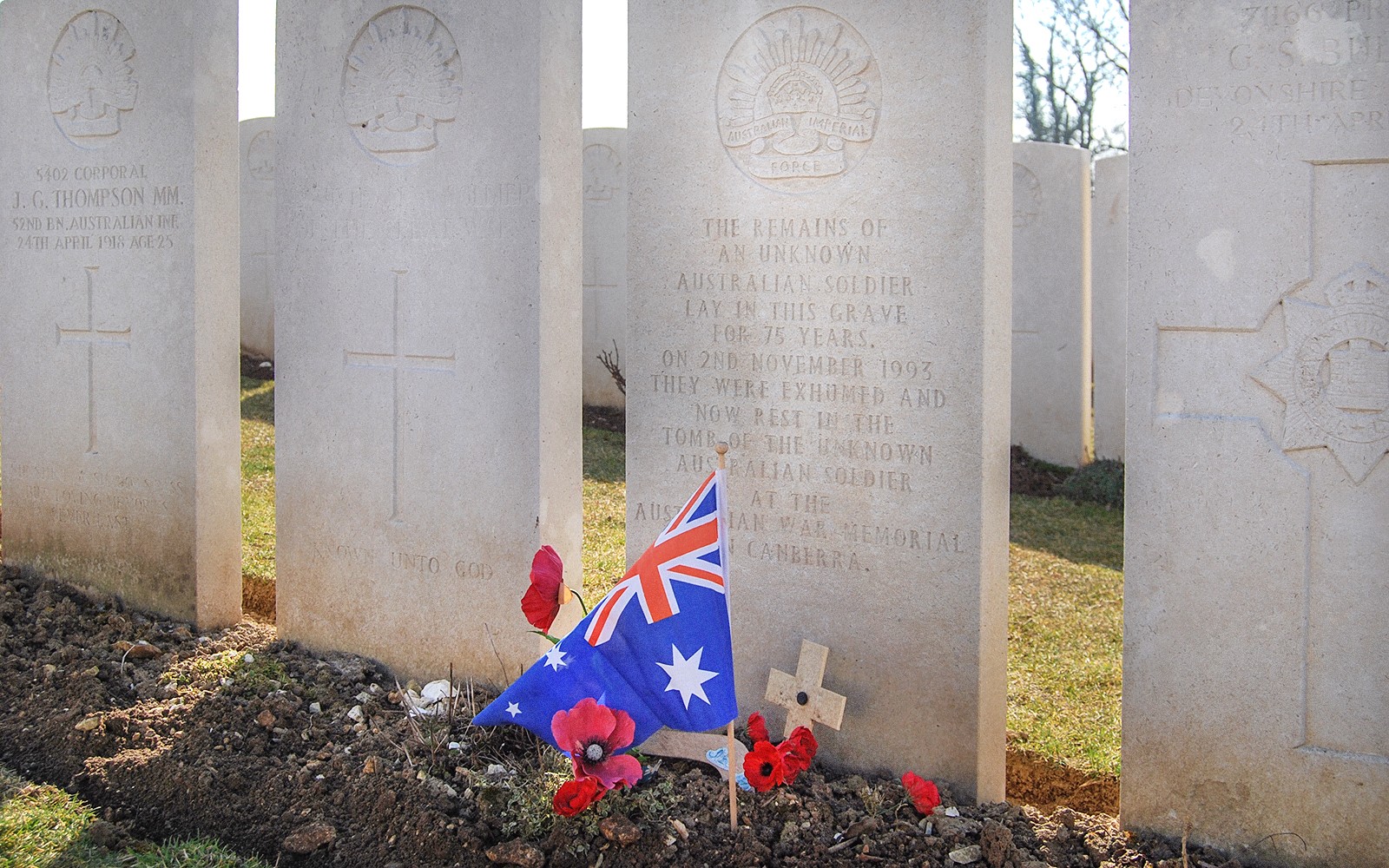 Australian soldier's grave with flag and poppies at Somme battlefield cemetery.
