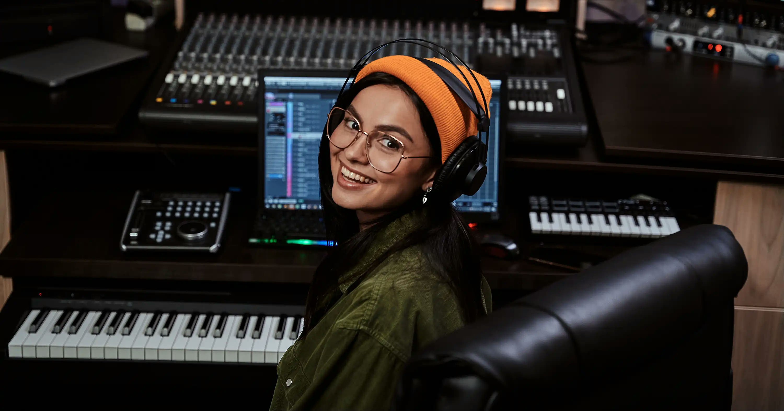 A female producer sitting in front of a keyboard and digital audio workstation