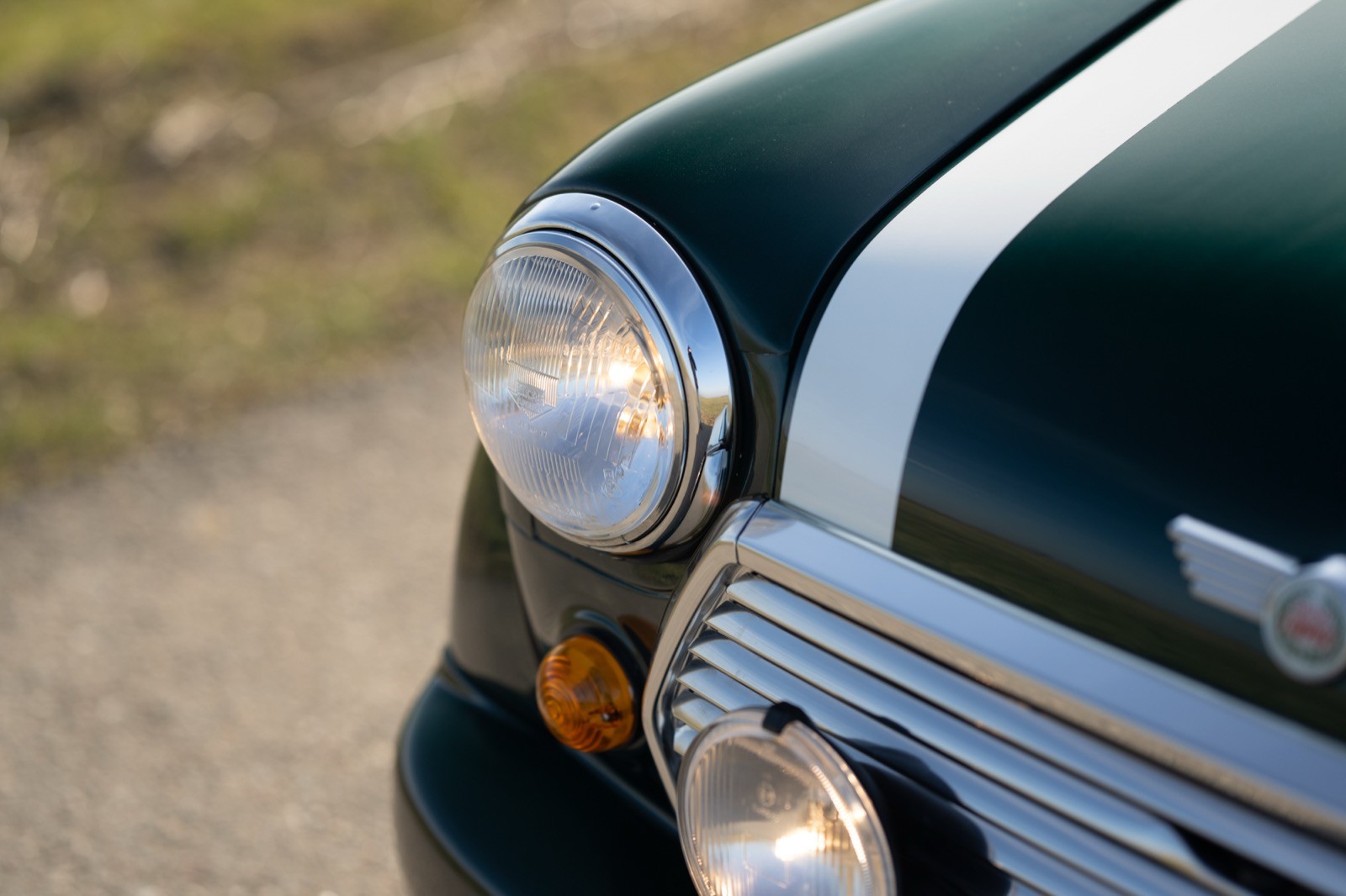 Close-up of a vintage car's front headlight and hood, showcasing a classic design and metallic details.